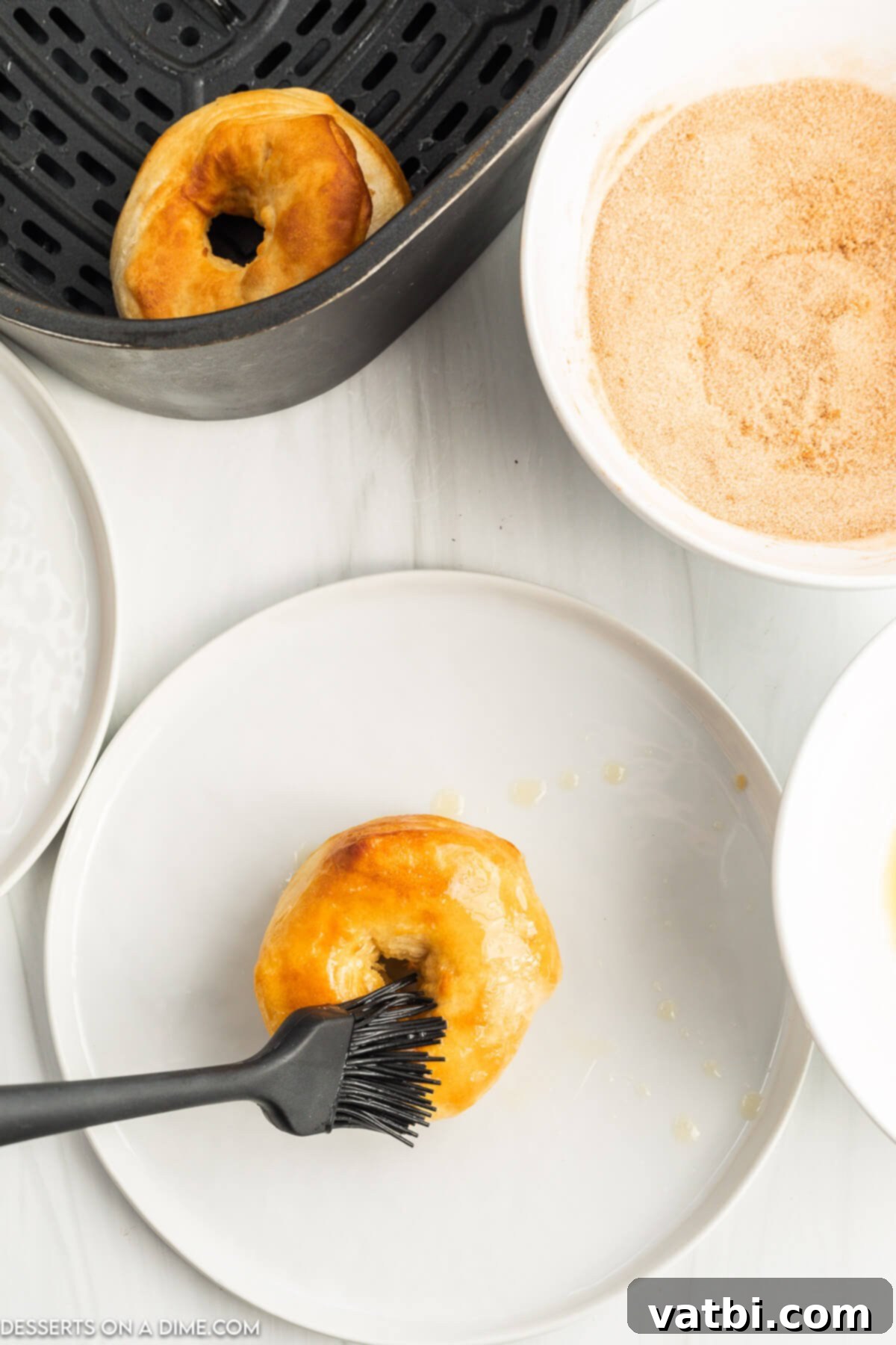 Delicious Air Fryer Donuts Made Easy 7 Butter being brushed on donut.