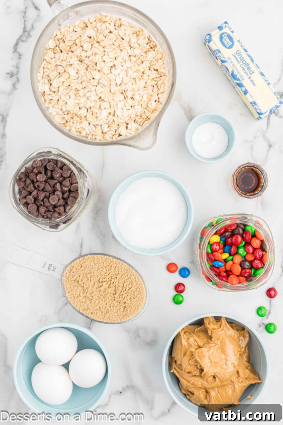 Ultimate Gluten-Free Monster Cookies 3 Various ingredients for Gluten-Free Monster Cookies laid out: butter, creamy peanut butter, brown sugar, eggs, vanilla extract, baking soda, old-fashioned oats, semi-sweet chocolate chips, and M&M's.