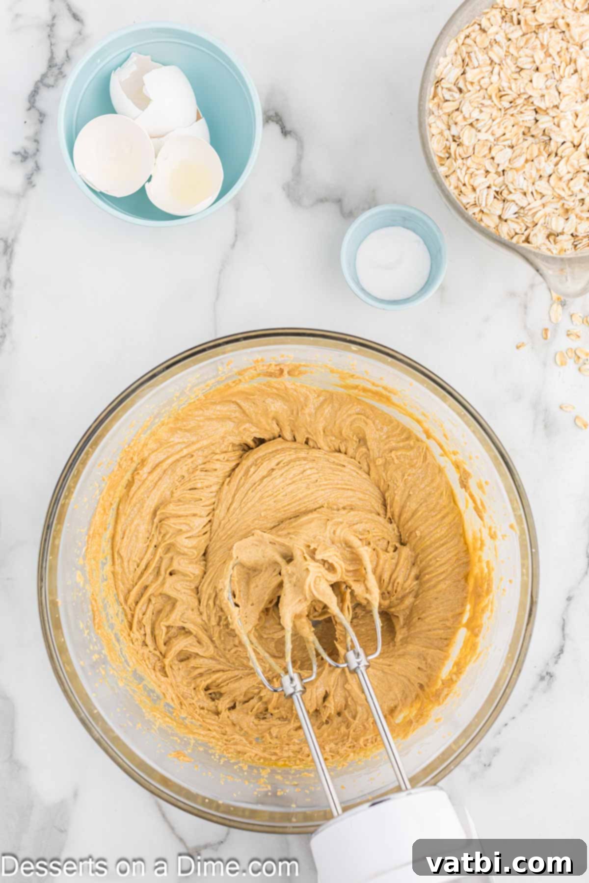 Ultimate Gluten-Free Monster Cookies 4 Creamy peanut butter and butter being creamed together in a large mixing bowl with an electric mixer.