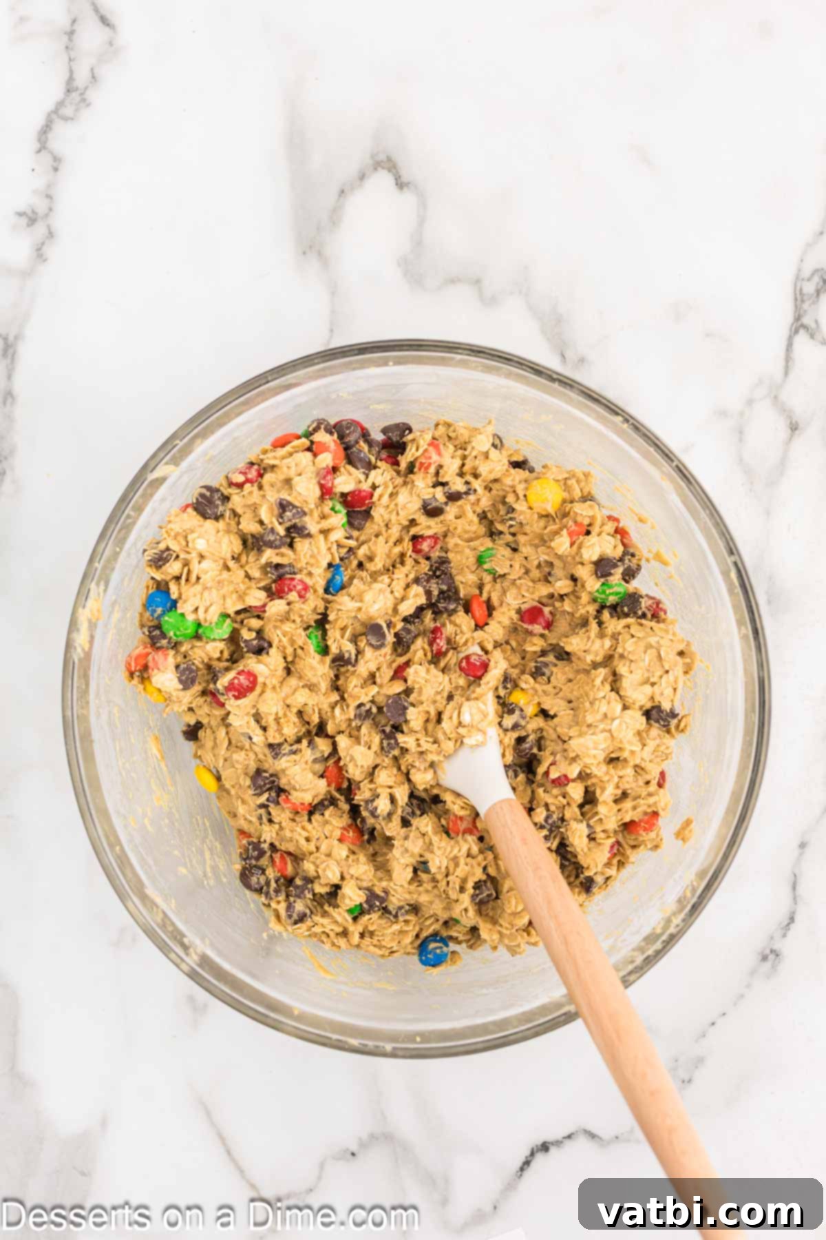 Ultimate Gluten-Free Monster Cookies 6 Colorful M&M's being folded into the gluten-free monster cookie dough in a mixing bowl.