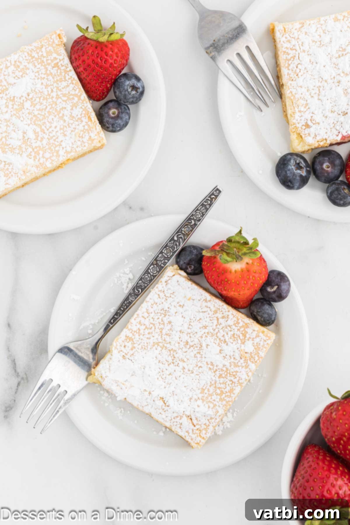 Paula Deen's Signature Ooey Gooey Butter Cake 2 Paula Deen Ooey Gooey Butter Cake cut into squares and served on a plate with fresh berries and a sprig of mint.