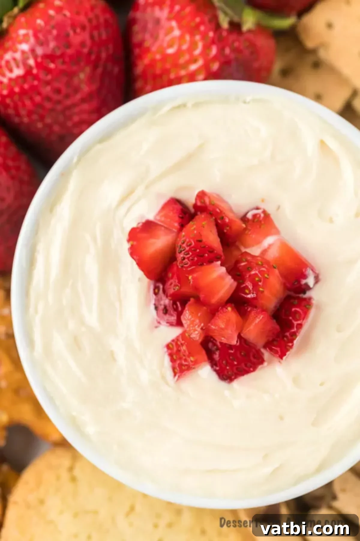 Creamy cheesecake dip in a white bowl, elegantly topped with fresh, vibrant diced strawberries, ready to be served.
