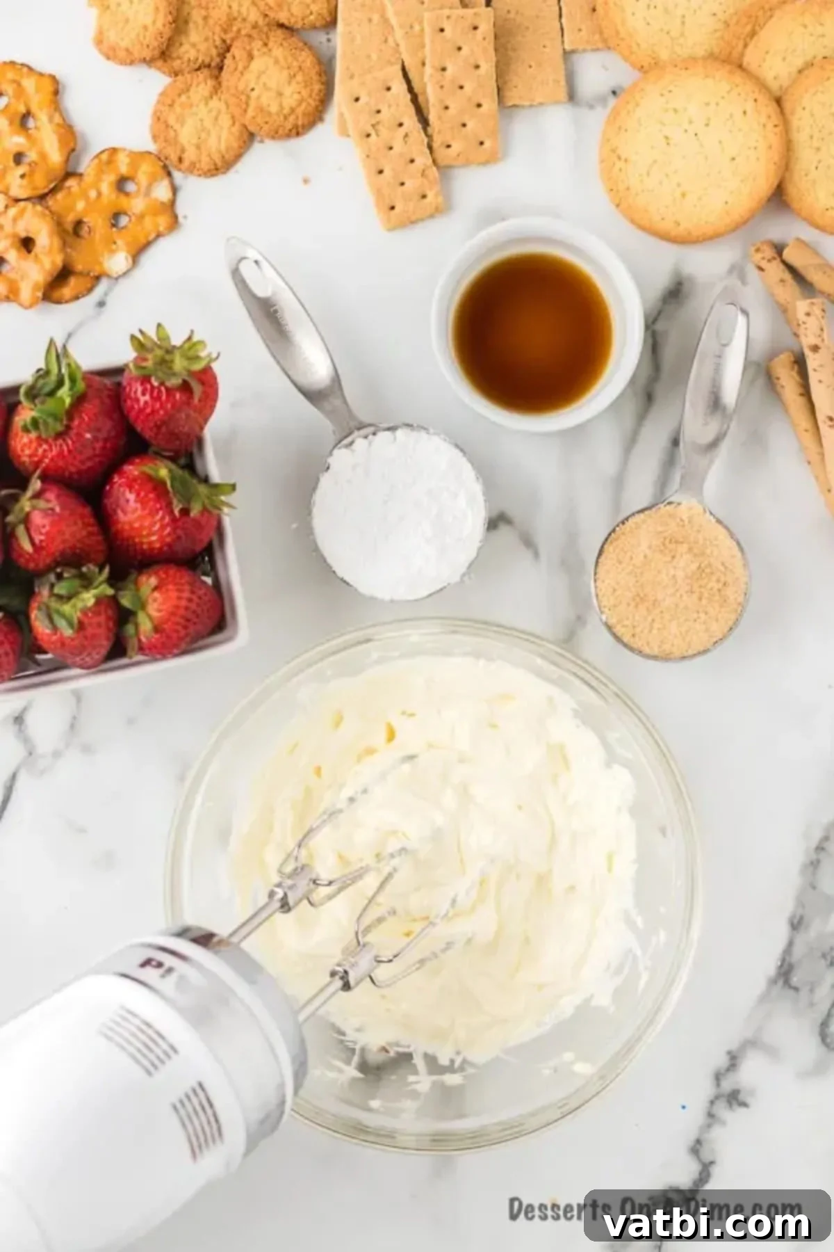 A mixing bowl with softened cream cheese being beaten by an electric hand mixer until smooth and fluffy.