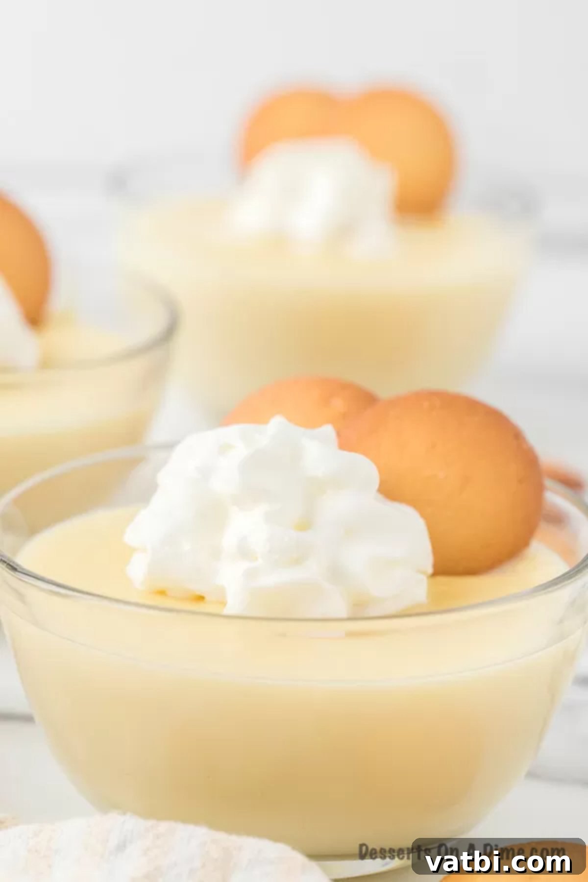 Creamy Homemade Vanilla Pudding 2 Vanilla pudding topped with whipped cream and vanilla wafers in a glass bowl