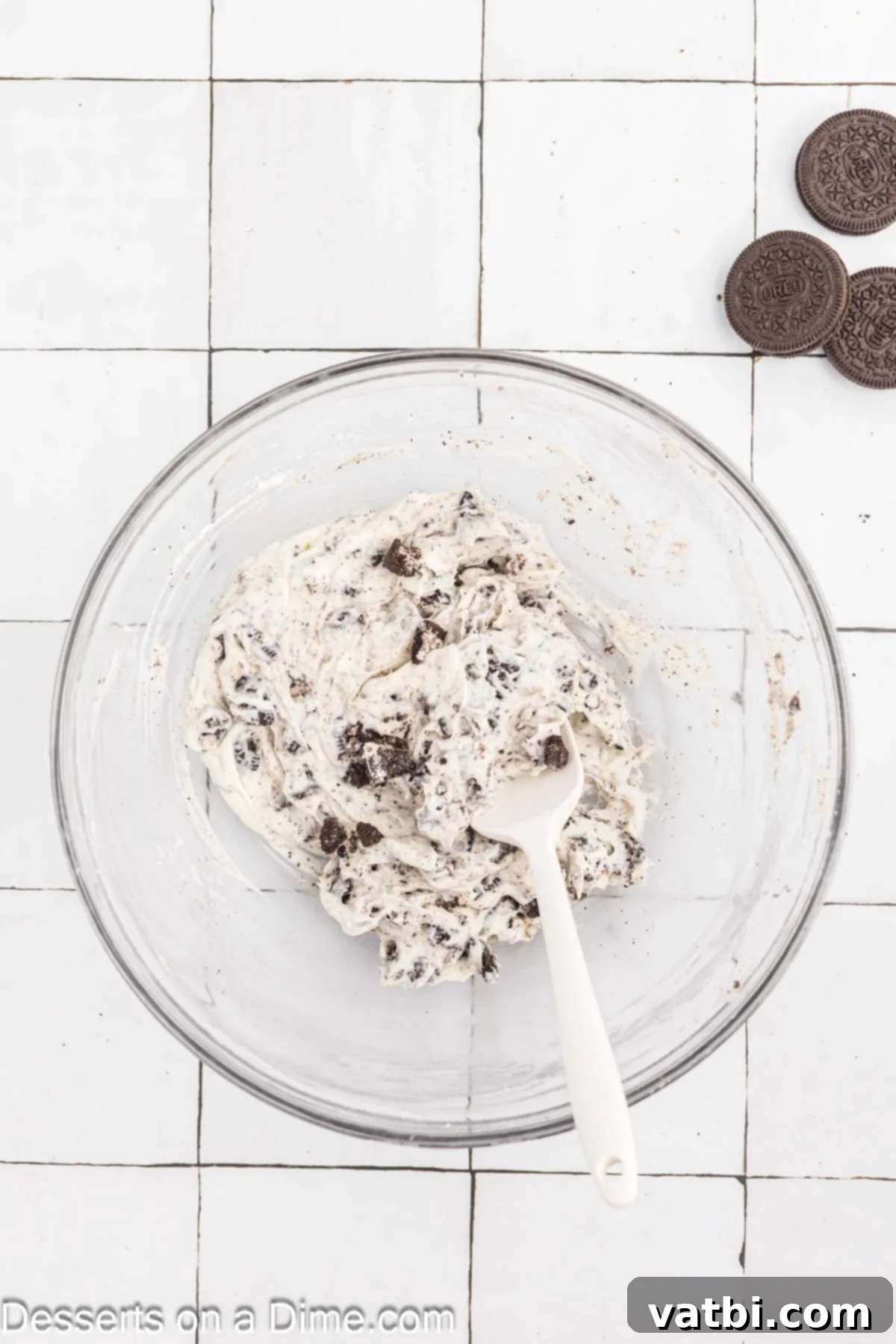 Crushed Oreo cookies folded into the cream cheese mixture in a bowl.