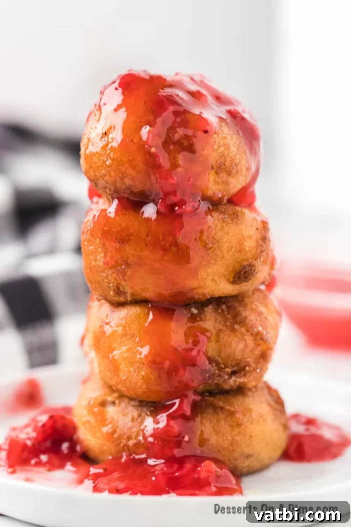 Golden Crisp Cheesecake Indulgence 12 Close up image of Deep Fried Cheesecake Bites stacked and drizzled with a rich strawberry sauce, ready to serve.