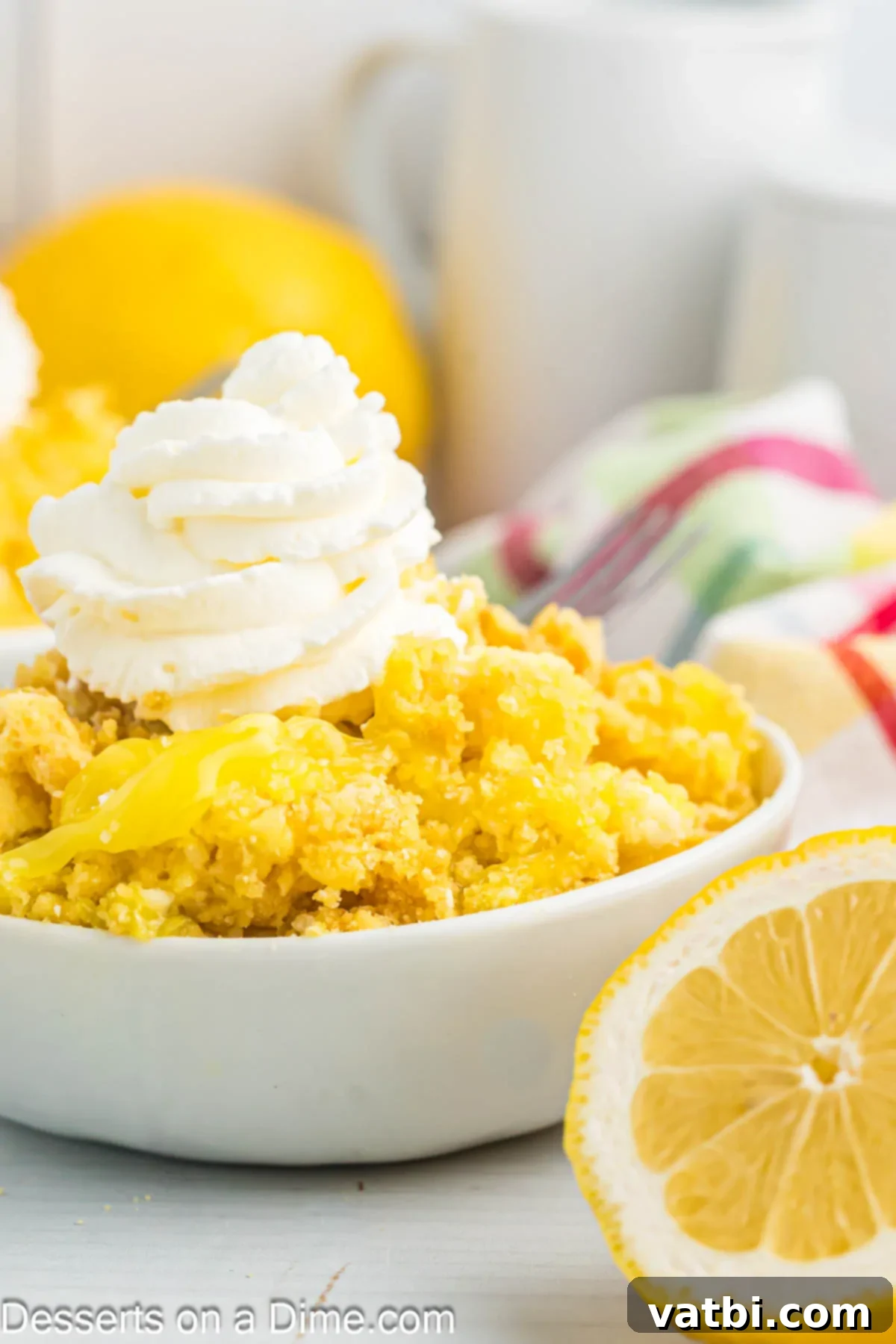 Effortless Lemon Bake 11 A generous serving of Lemon Dump Cake in a bowl, crowned with a dollop of fluffy whipped cream, inviting a bite.
