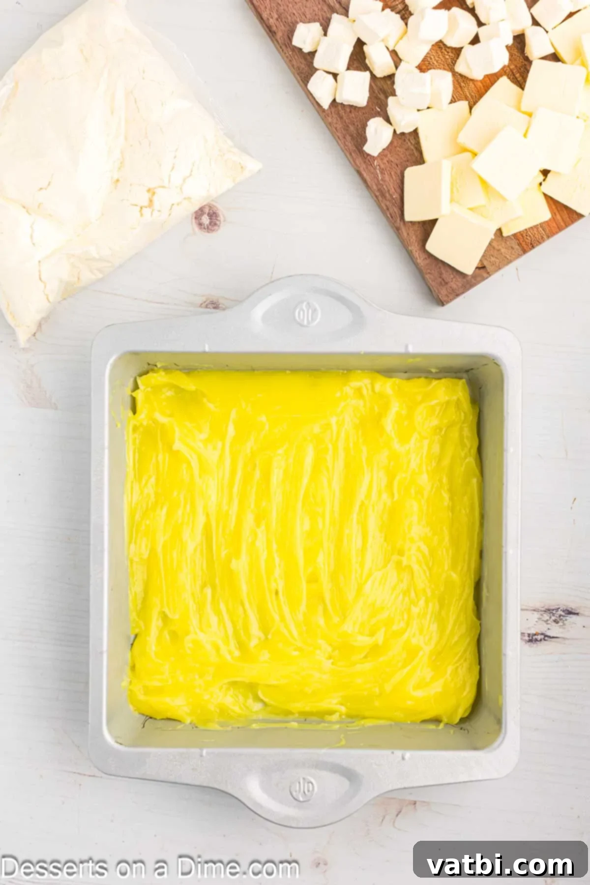 Effortless Lemon Bake 5 Lemon pie filling evenly spread across the bottom of a 9x9 inch baking pan, forming the base layer for the dump cake.