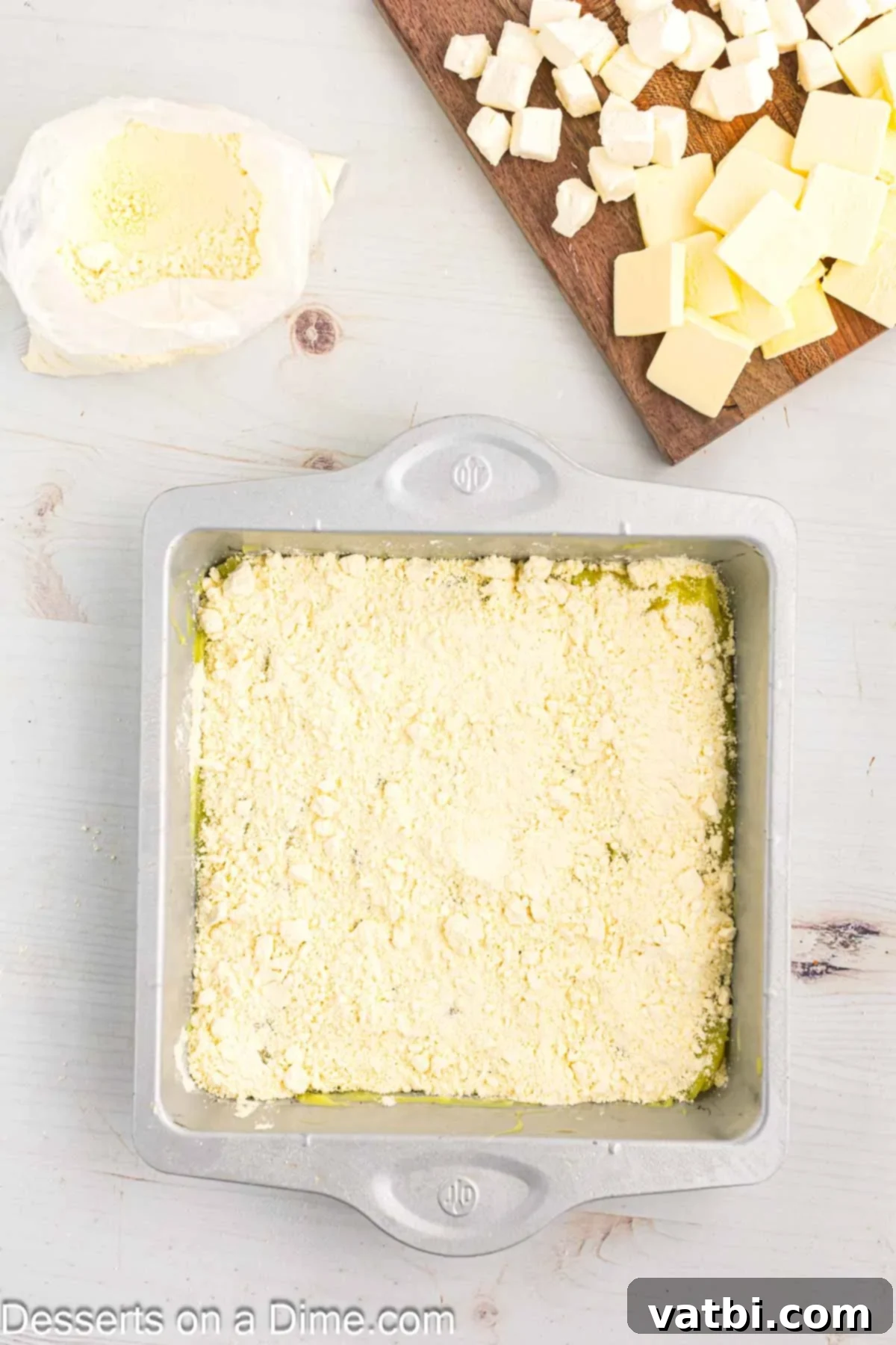 Effortless Lemon Bake 6 Half of the dry yellow cake mix is lightly sprinkled over the lemon pie filling in the baking pan, creating an even layer.
