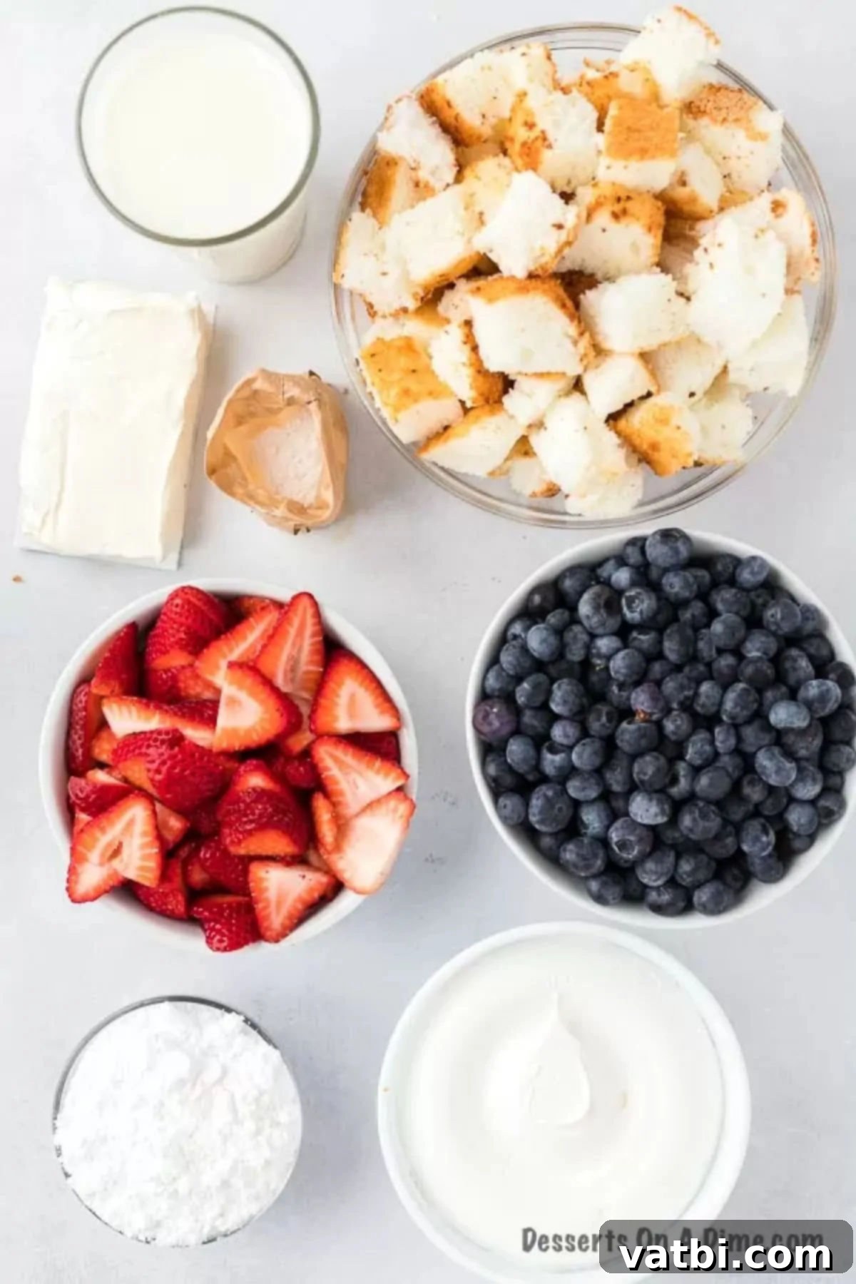 Patriotic Trifle 3 Ingredients laid out to make a Red, White, and Blue Trifle: angel food cake cubes, vanilla pudding mix, cream cheese, Cool Whip, and fresh strawberries and blueberries.