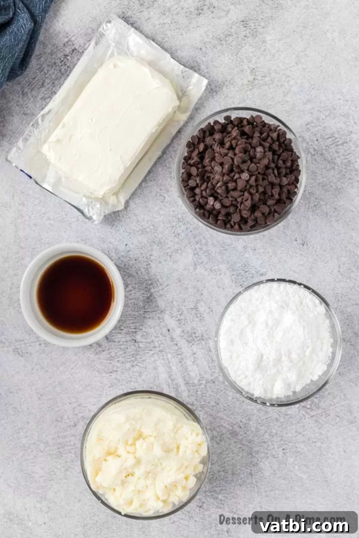 Decadent Cannoli Dip 3 Fresh ingredients for making cannoli dip, including softened cream cheese, whole milk ricotta, powdered sugar, vanilla extract, and mini chocolate chips, neatly arranged on a countertop.