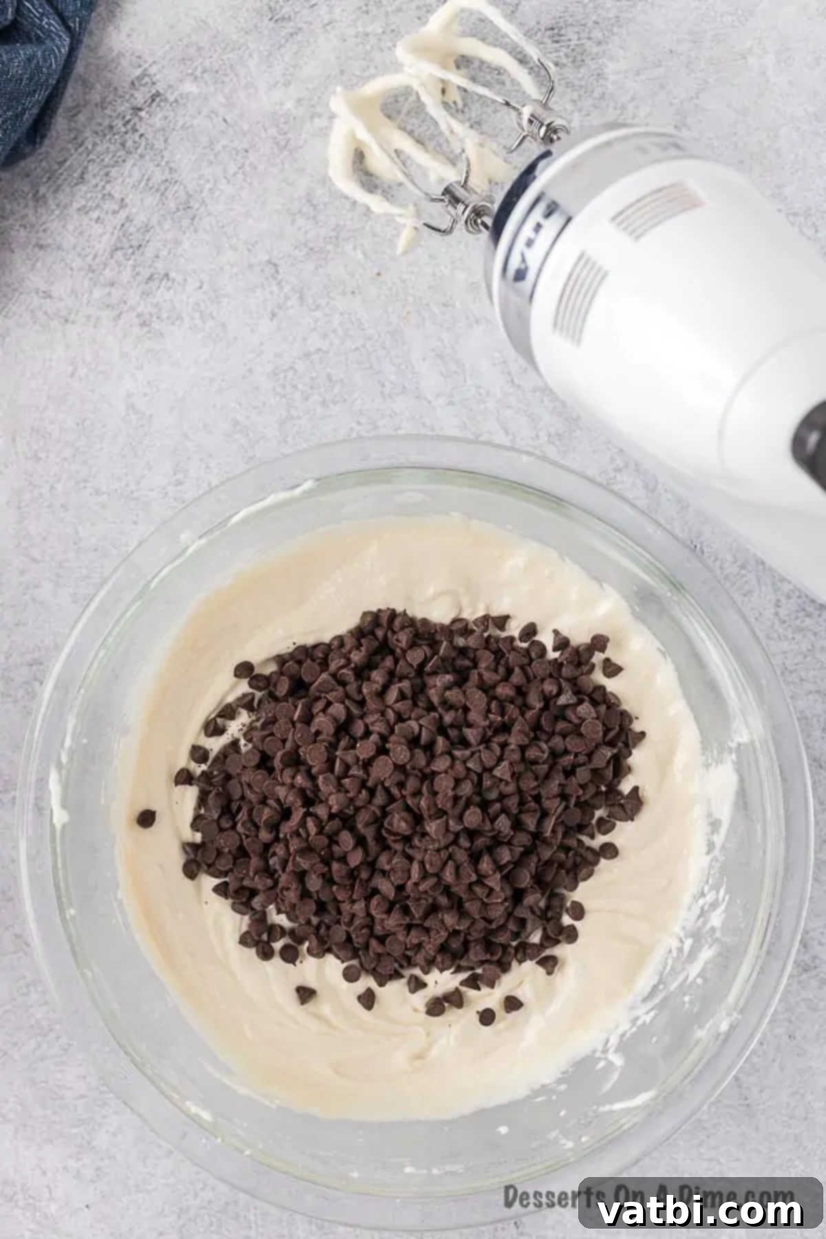 Decadent Cannoli Dip 6 Miniature chocolate chips being gently folded into the smooth, white cannoli dip mixture with a spatula.
