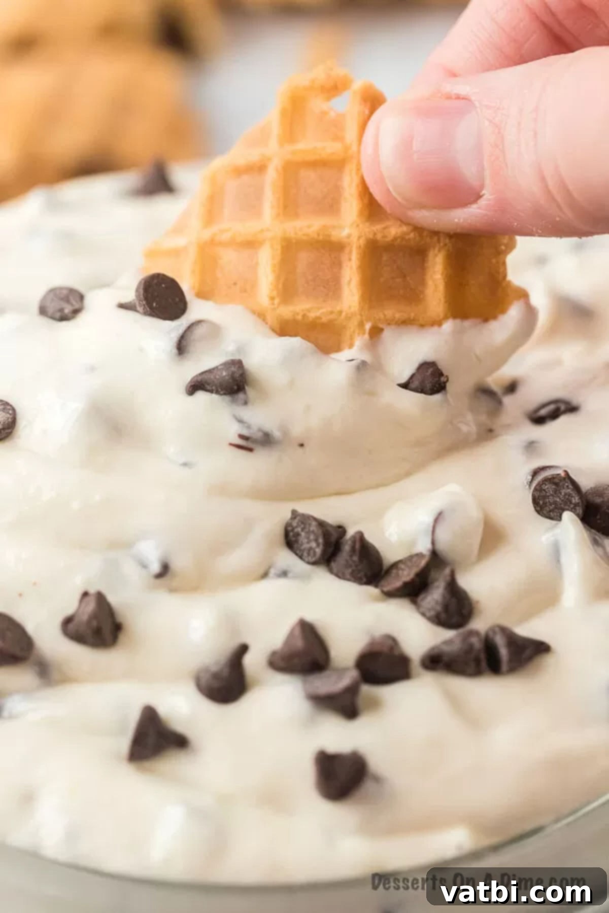 Decadent Cannoli Dip 8 A crispy waffle cone piece being dipped into the rich and creamy cannoli dip, showing its perfect texture for scooping.