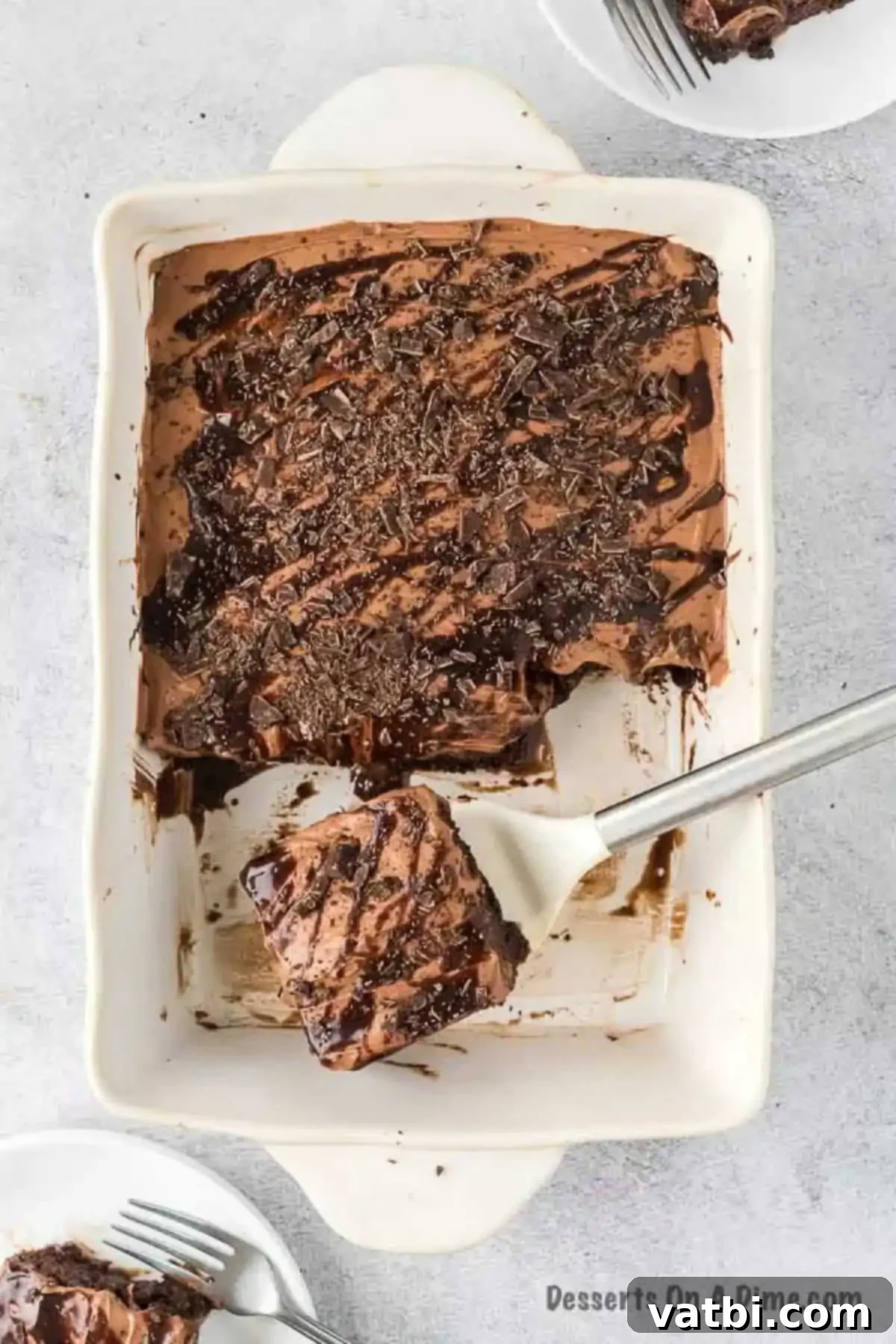 A serving of chocolate poke cake being lifted from the pan, showcasing its rich layers and tempting appearance, ready to be placed on a plate.