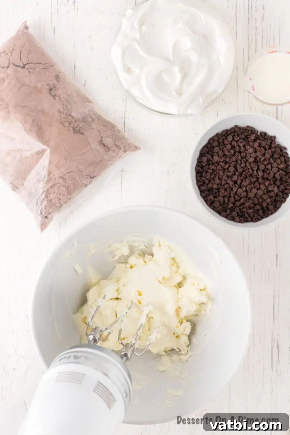 Sweet Brownie Indulgence 4 Softened cream cheese being beaten in a bowl with a hand mixer.