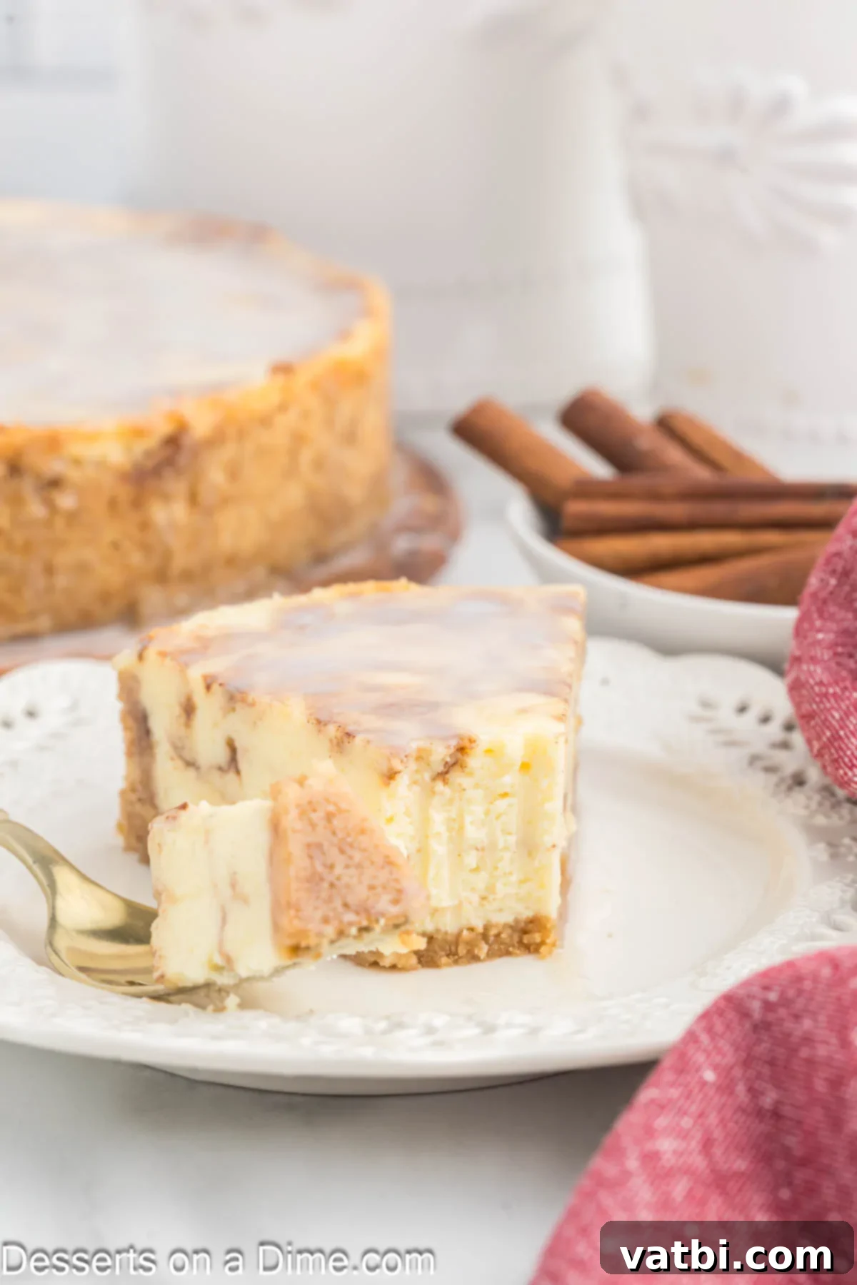 Honey Cinnamon Swirl Cheesecake 12 A fully chilled Honey Bun Cheesecake, sliced and ready for serving on a white plate, adorned with its signature glaze.