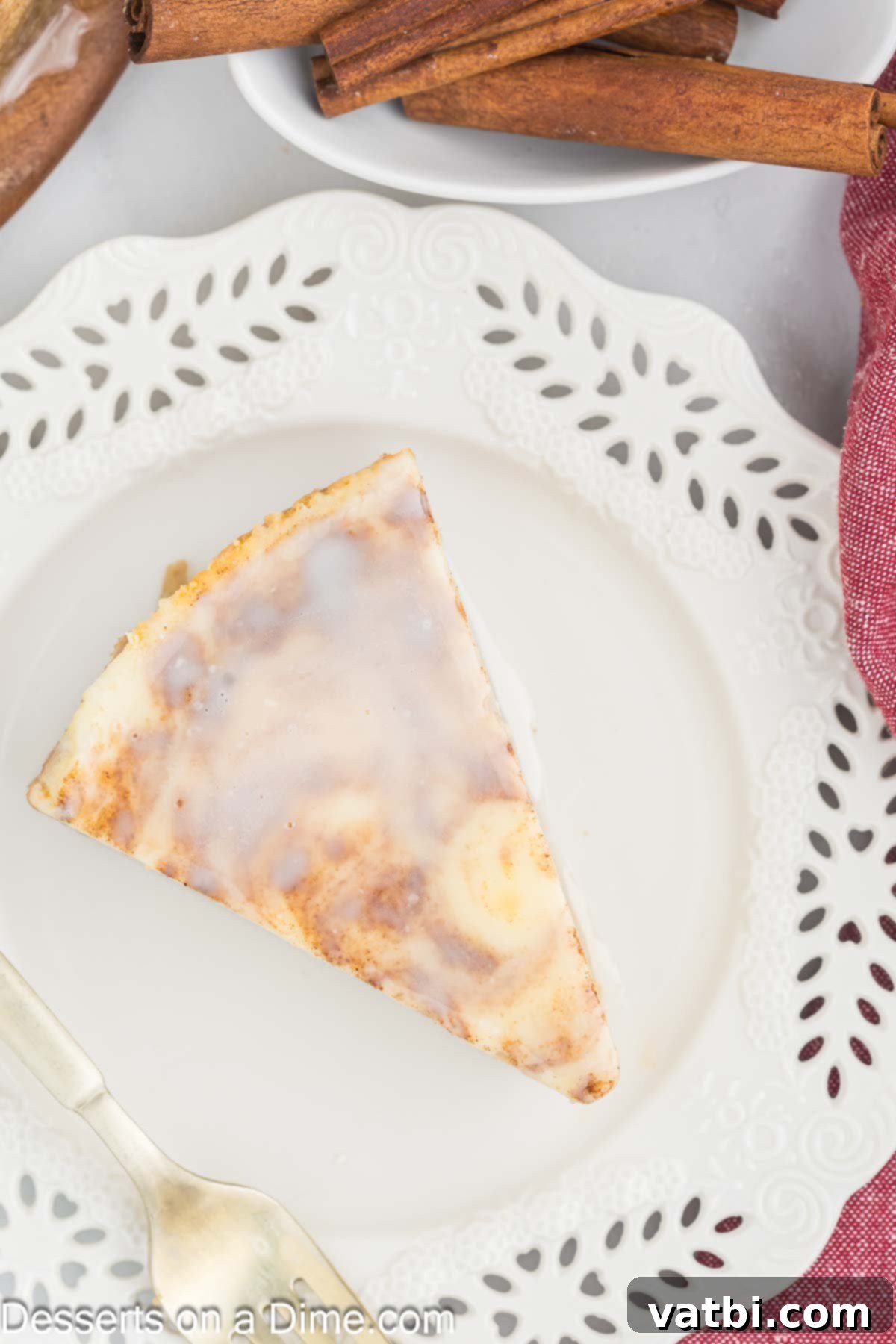 Honey Cinnamon Swirl Cheesecake 13 A slice of Honey Bun Cheesecake on a plate, featuring the cinnamon swirl and a generous drizzle of white glaze, ready to be enjoyed.