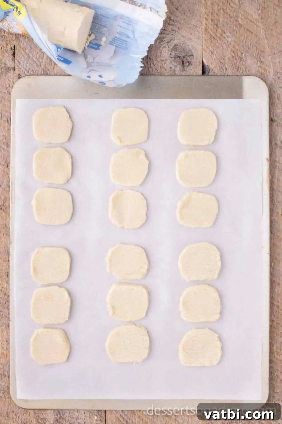 Effortless Snowman Cookie Fun 4 Three cookie dough portions gently pressed together on a baking sheet to form a snowman shape before baking.