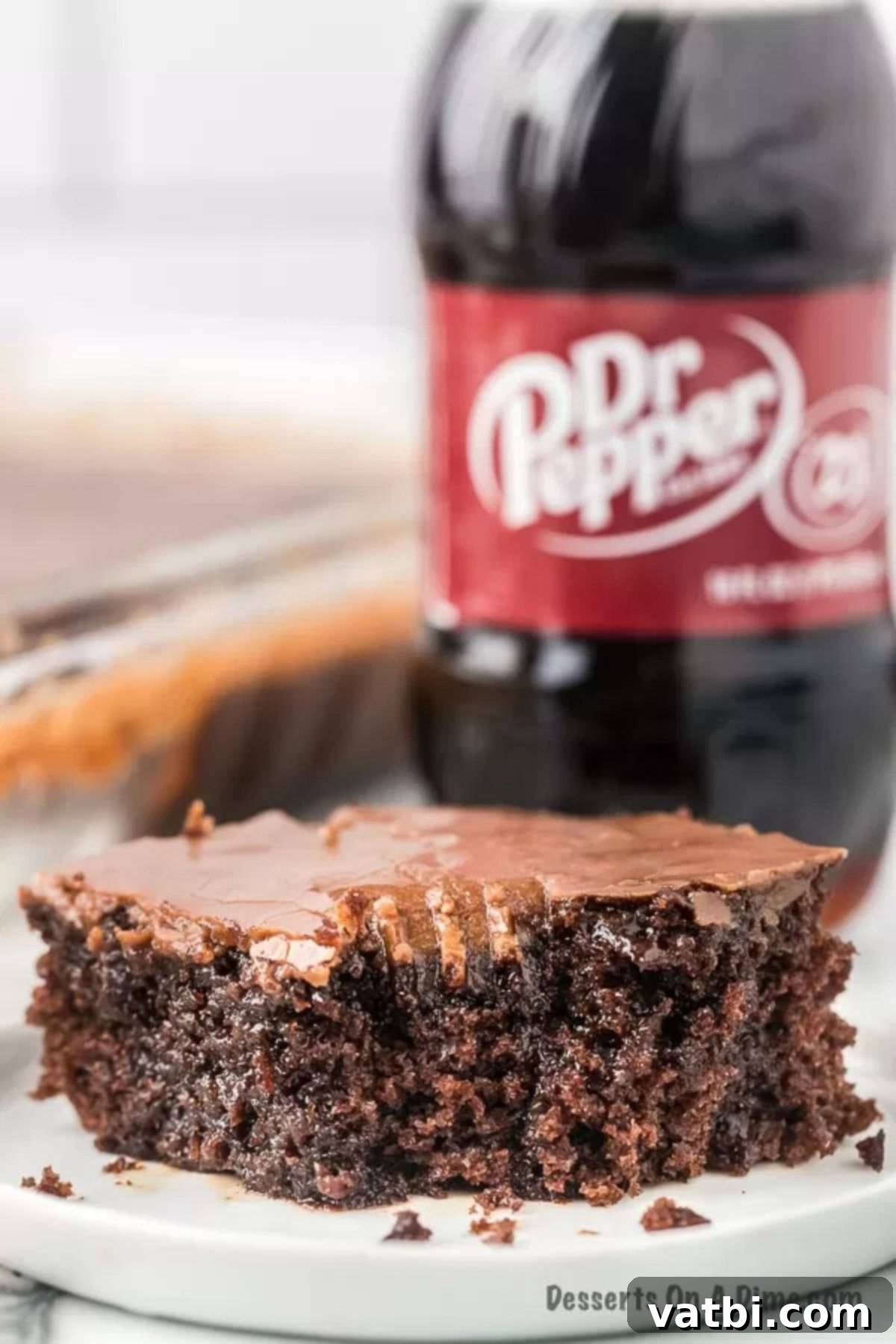 Dark Dr Pepper Decadence 2 Closeup photo of cake slice in front of dr pepper bottle.