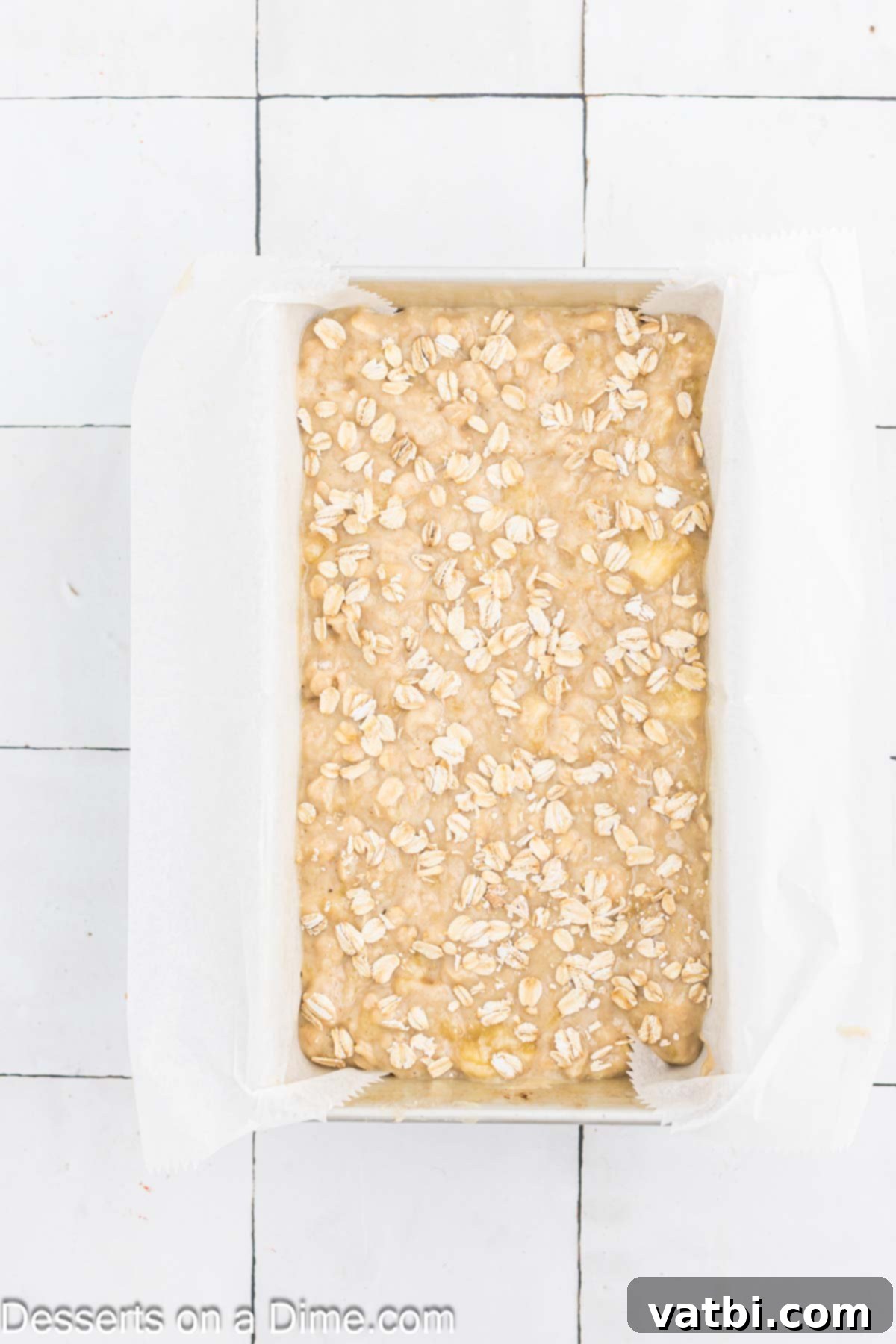 Delicious Banana Oat Bread 8 Oatmeal Banana Bread batter is poured into the parchment-lined loaf pan, topped with additional oats.