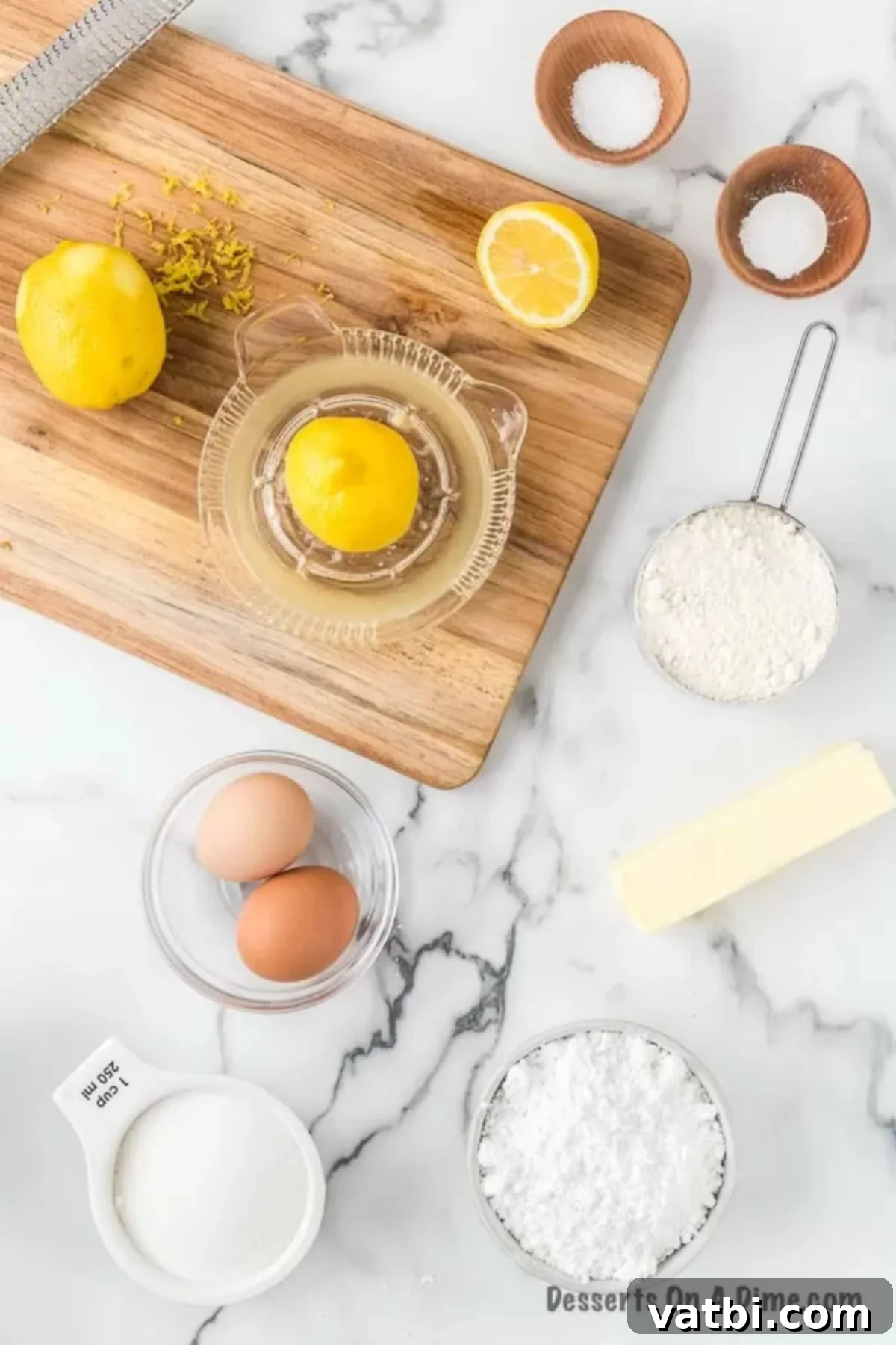 Zesty Lemon Brownie Bliss 3 Ingredients for lemon brownies laid out: butter, sugar, lemon zest, eggs, lemon juice, flour, baking powder, salt, and powdered sugar.