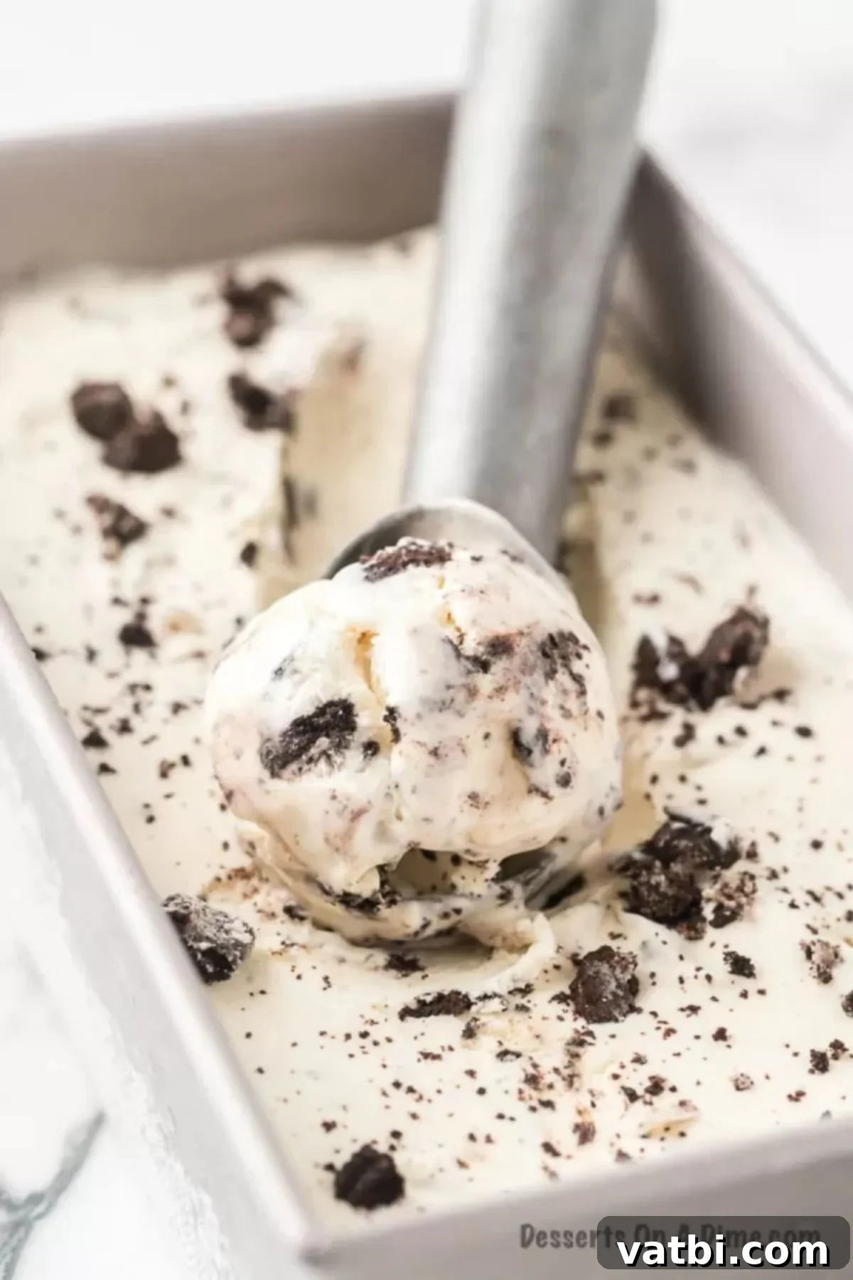 Swirled Cookie Bliss 2 Scooping rich homemade Cookies and Cream Ice Cream from a loaf pan, revealing generous chunks of Oreo cookies.