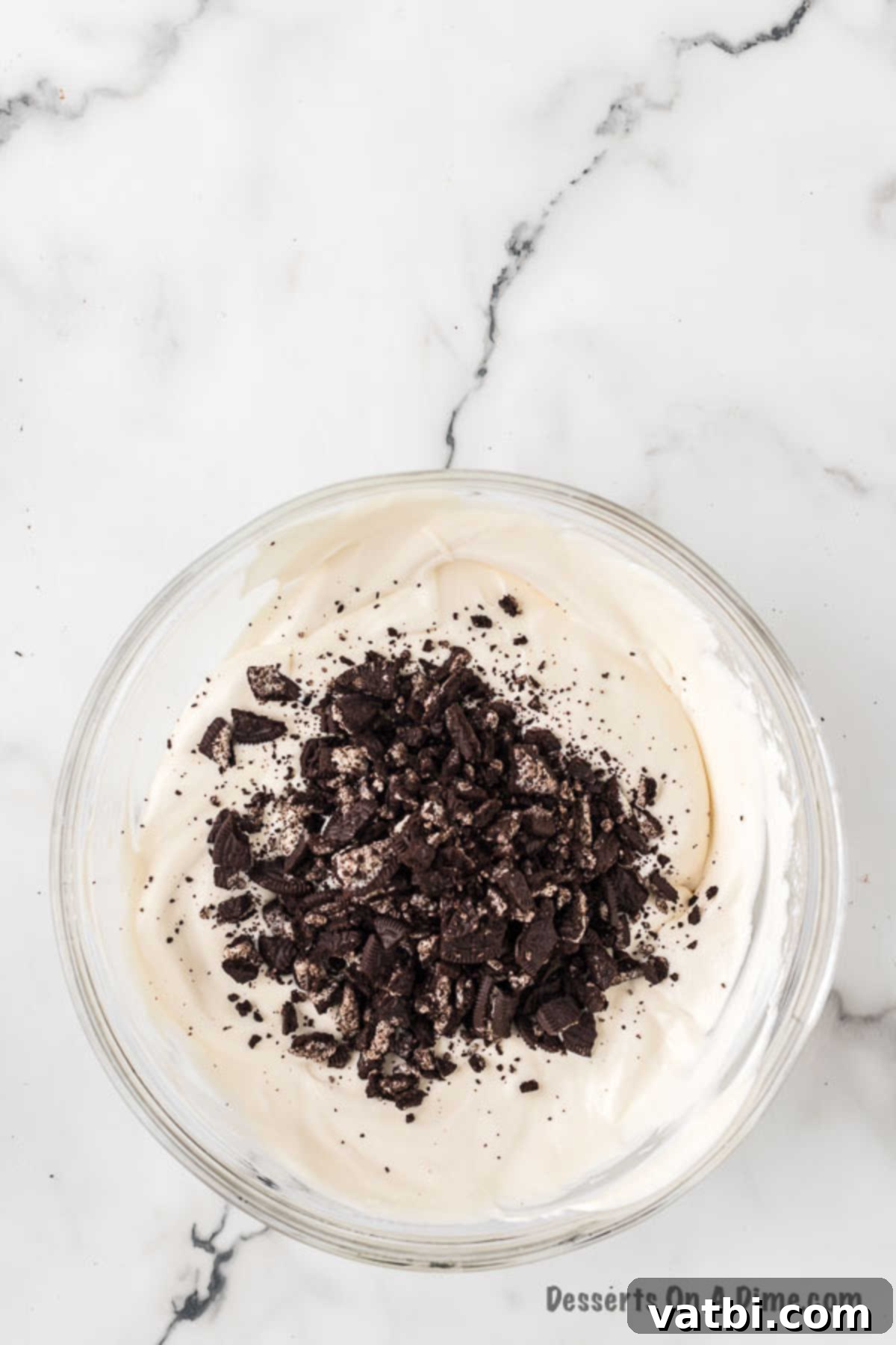 Swirled Cookie Bliss 8 Crushed Oreo cookies folded into the creamy ice cream base mixture in a bowl.