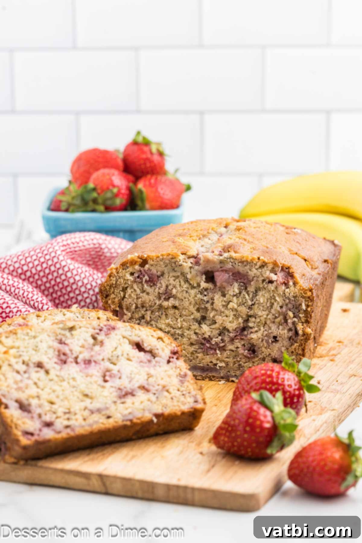 Blushing Berry Banana Bread 2 A beautifully sliced loaf of Strawberry Banana Bread, showcasing its moist texture and pockets of fresh strawberries.