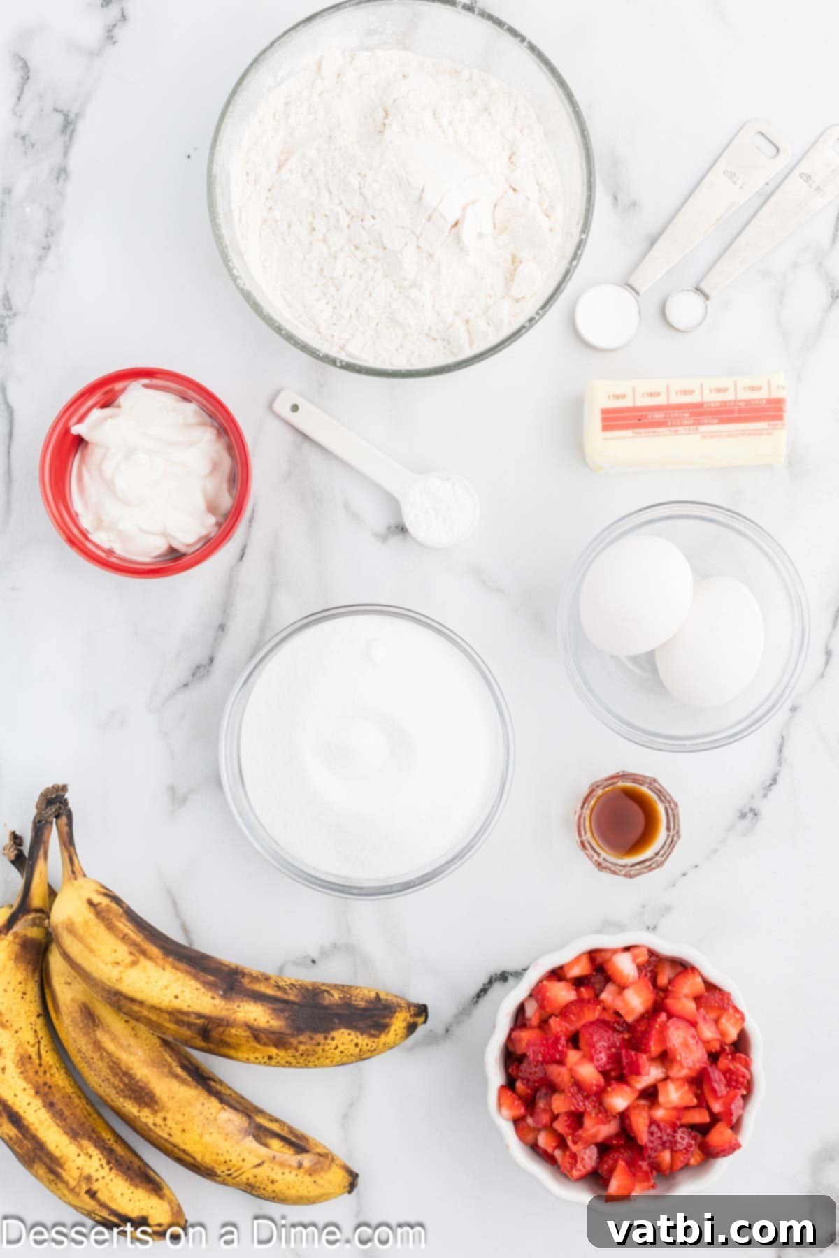 Blushing Berry Banana Bread 3 All the necessary ingredients for Strawberry Banana Bread laid out on a table: flour, baking soda, sugar, softened butter, sour cream, ripe bananas, eggs, vanilla extract, and fresh strawberries.