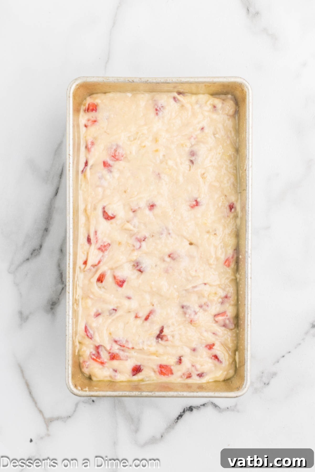 Blushing Berry Banana Bread 7 The strawberry banana bread batter spread evenly into a prepared loaf pan, ready for baking.