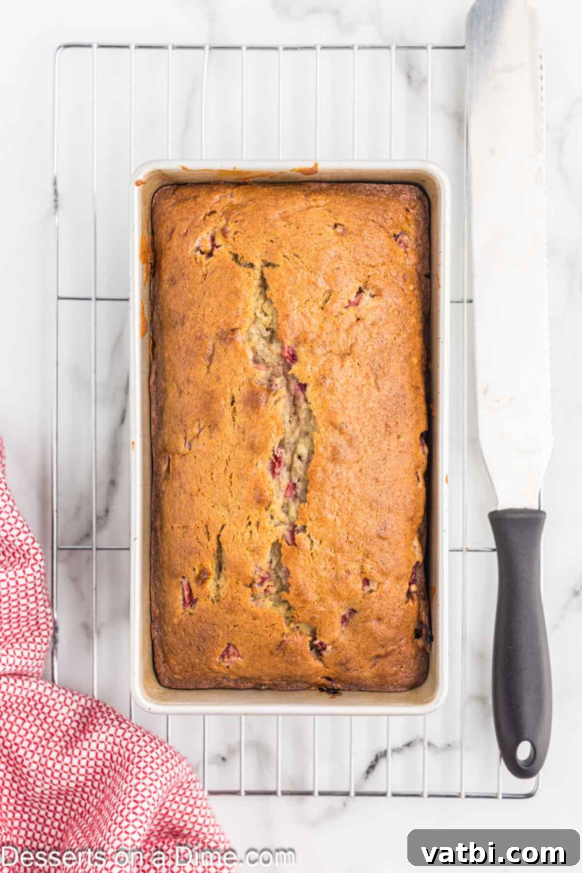 Blushing Berry Banana Bread 8 Freshly baked Strawberry Banana Bread cooling in its loaf pan before being turned out onto a wire rack.