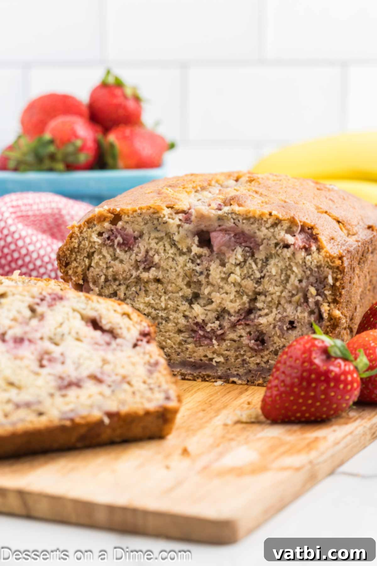 Blushing Berry Banana Bread 10 A hand slicing a fresh loaf of Strawberry Banana Bread, showing the perfectly baked crust and fruit-filled interior.