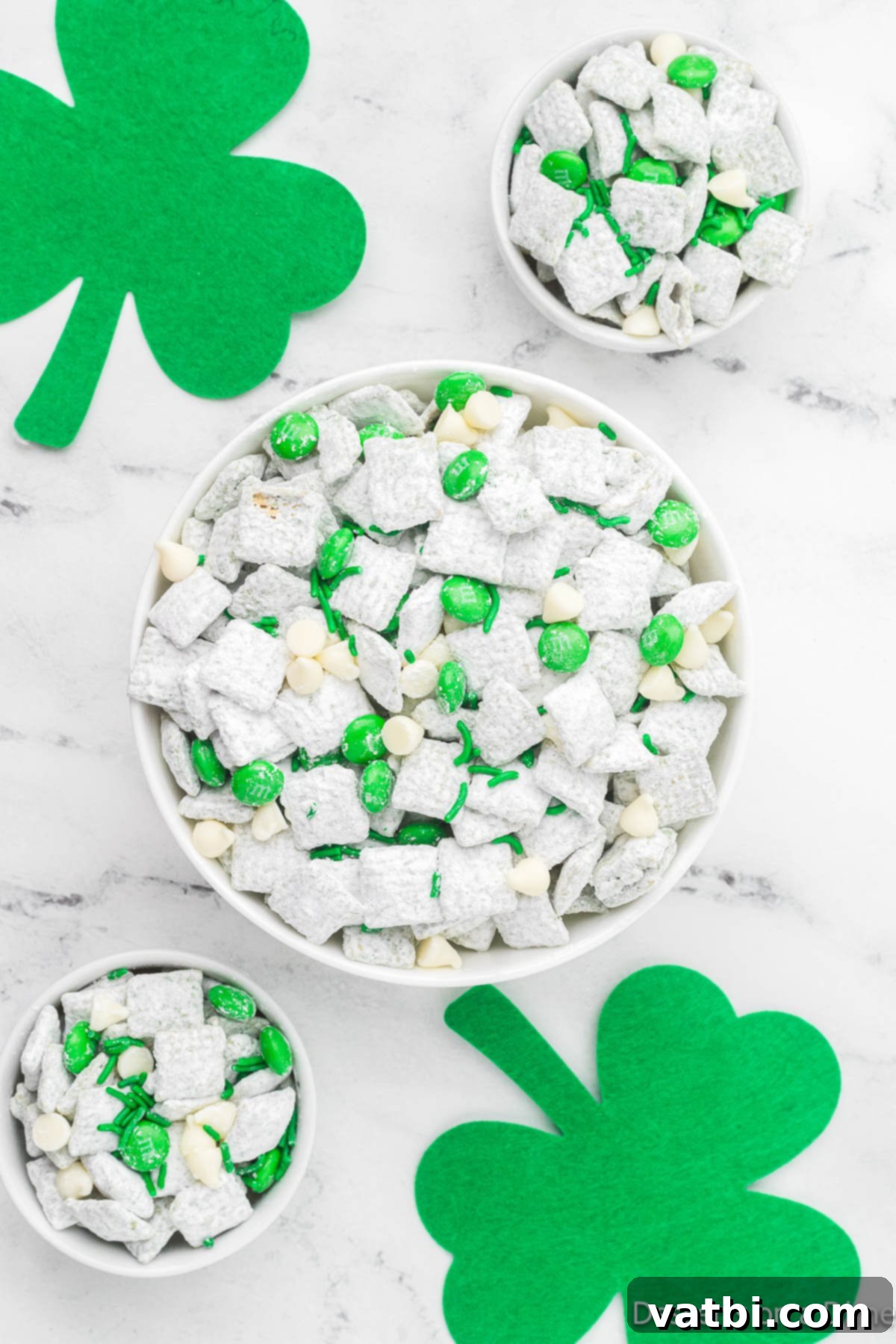 A bowl overflowing with festive St. Patrick's Day Puppy Chow, adorned with green candy and sprinkles.