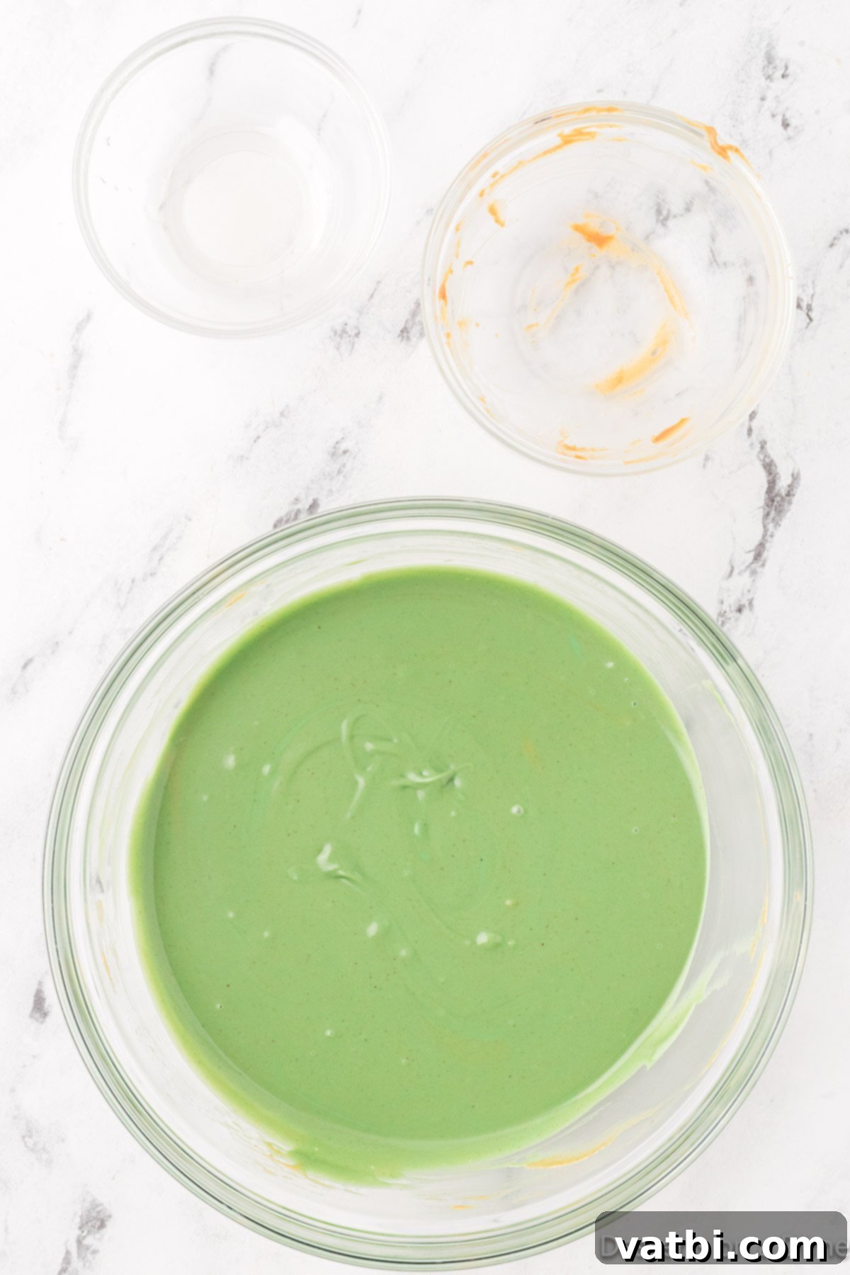 The melted green candy melts, peanut butter, and vegetable oil mixture, smooth and ready to coat the cereal.