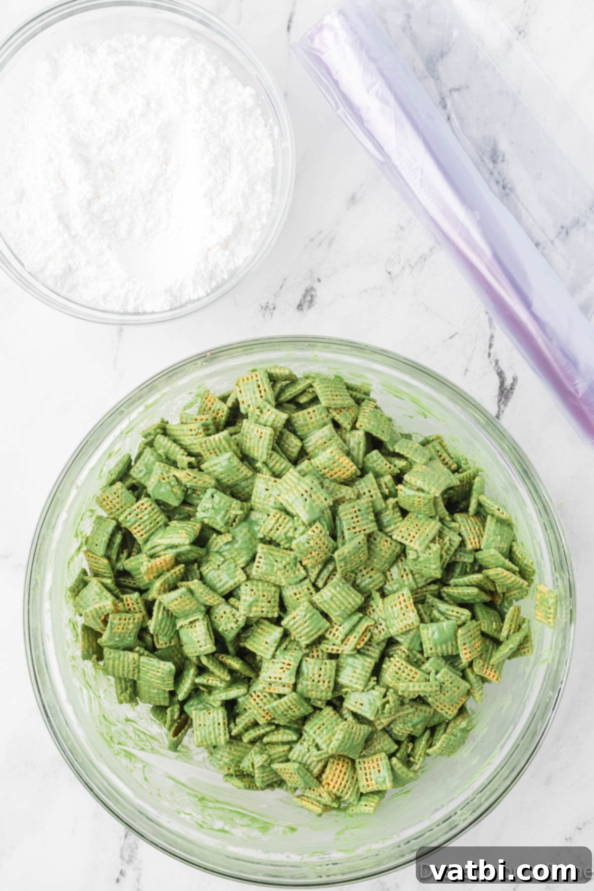 Chex cereal being mixed with the green candy melt and peanut butter coating in a large bowl.