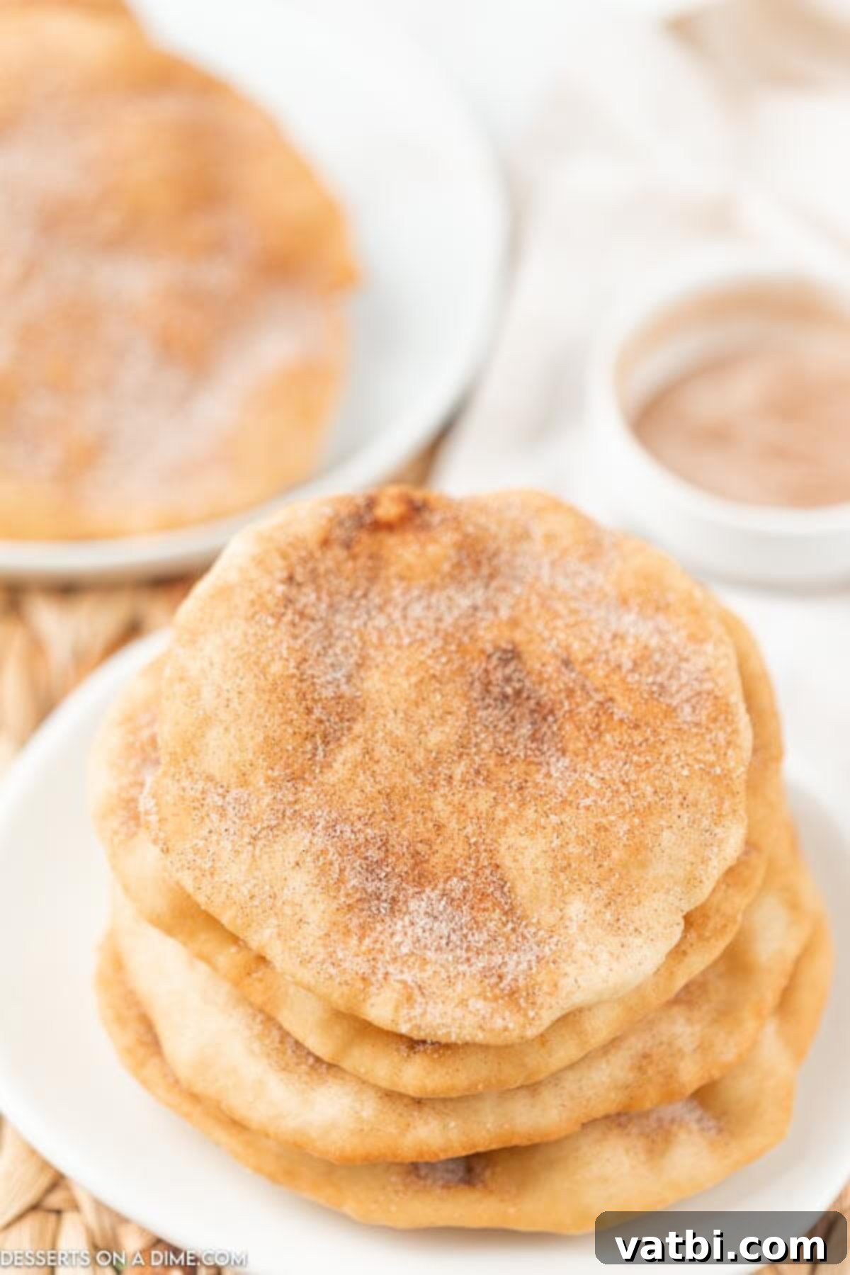 Homemade Elephant Ear Perfection 14 Four perfectly golden-brown elephant ears, expertly fried and generously coated with a sweet cinnamon sugar topping, neatly stacked on a white serving plate, inviting a delicious bite.