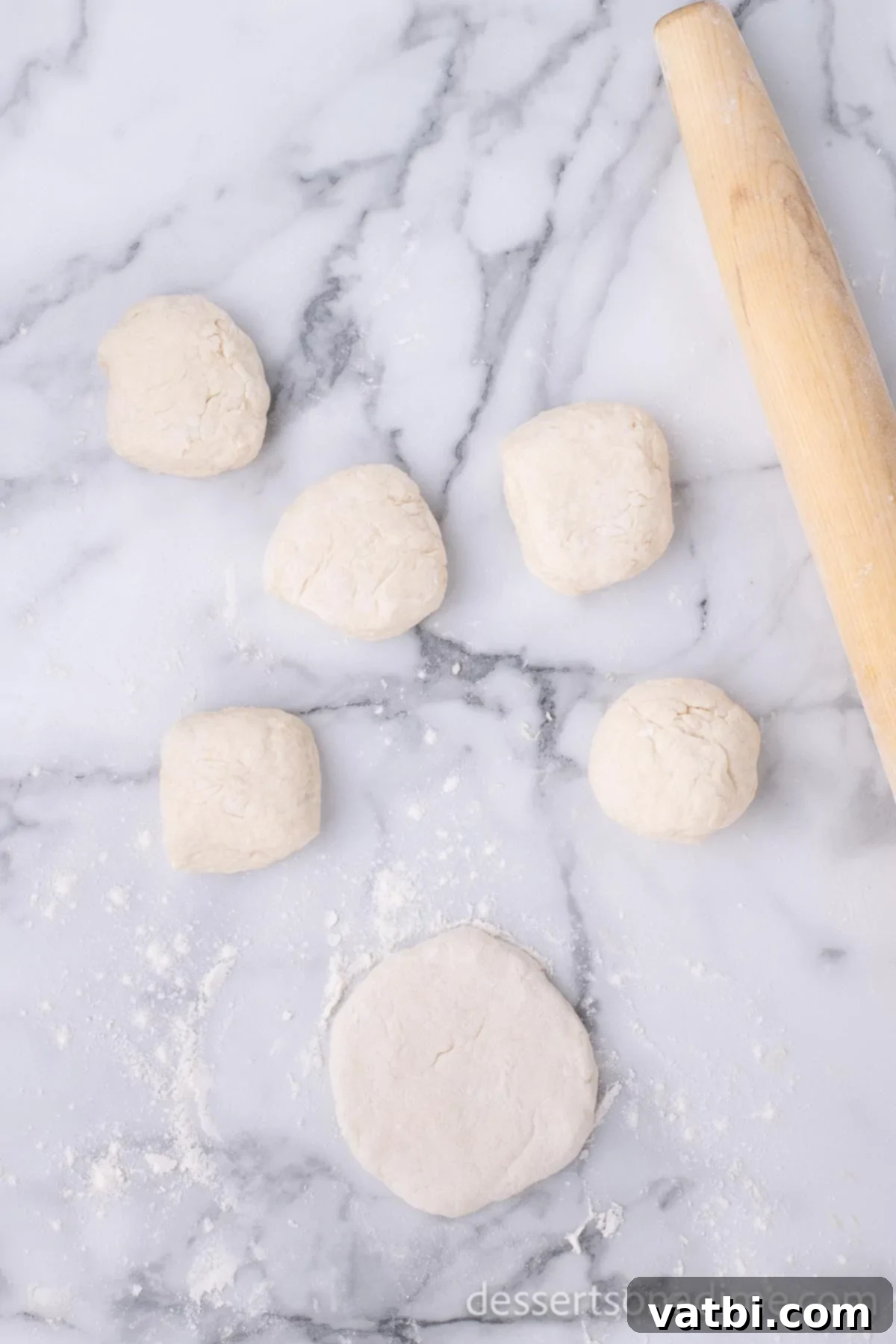 Homemade Elephant Ear Perfection 8 Each of the six dough pieces rolled into a small ball, with one ball flattened into a roughly ½-inch thick circular disc, showcasing the desired shape for frying.