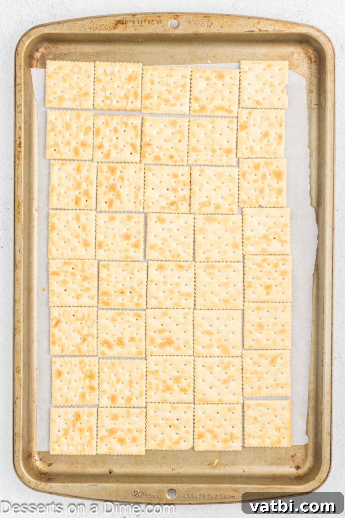 Saltine crackers arranged in a single layer on a baking sheet.