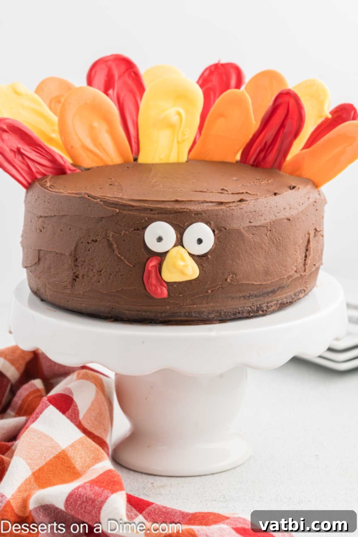 Colorful candy feathers meticulously added around the back edge of the frosted turkey cake.