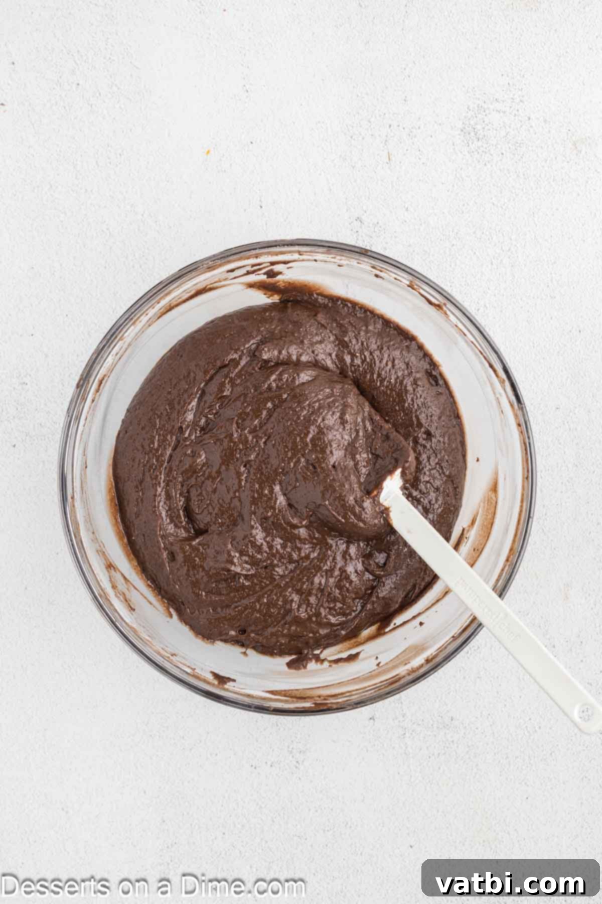 Dark chocolate cake batter in a large mixing bowl, ready to be poured into pans.