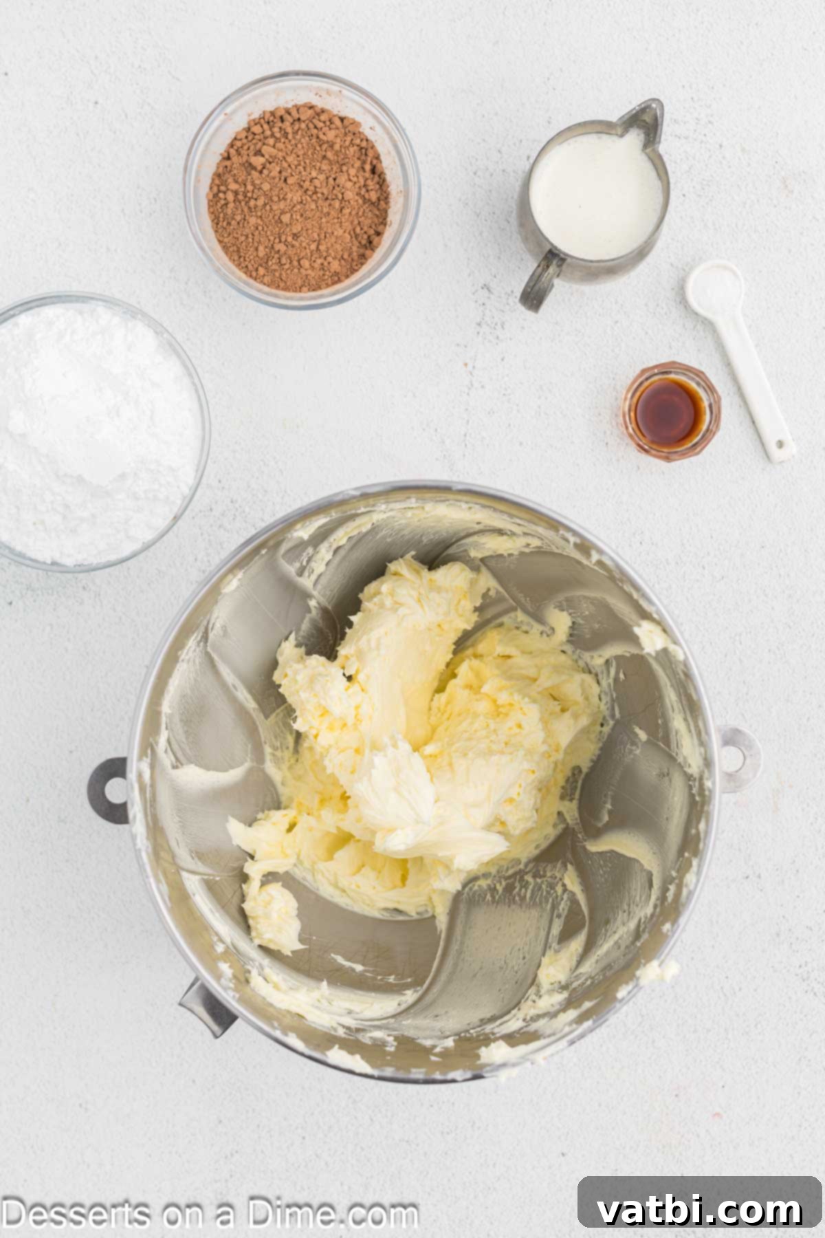 Softened unsalted butter being beaten until light and fluffy in a mixing bowl.
