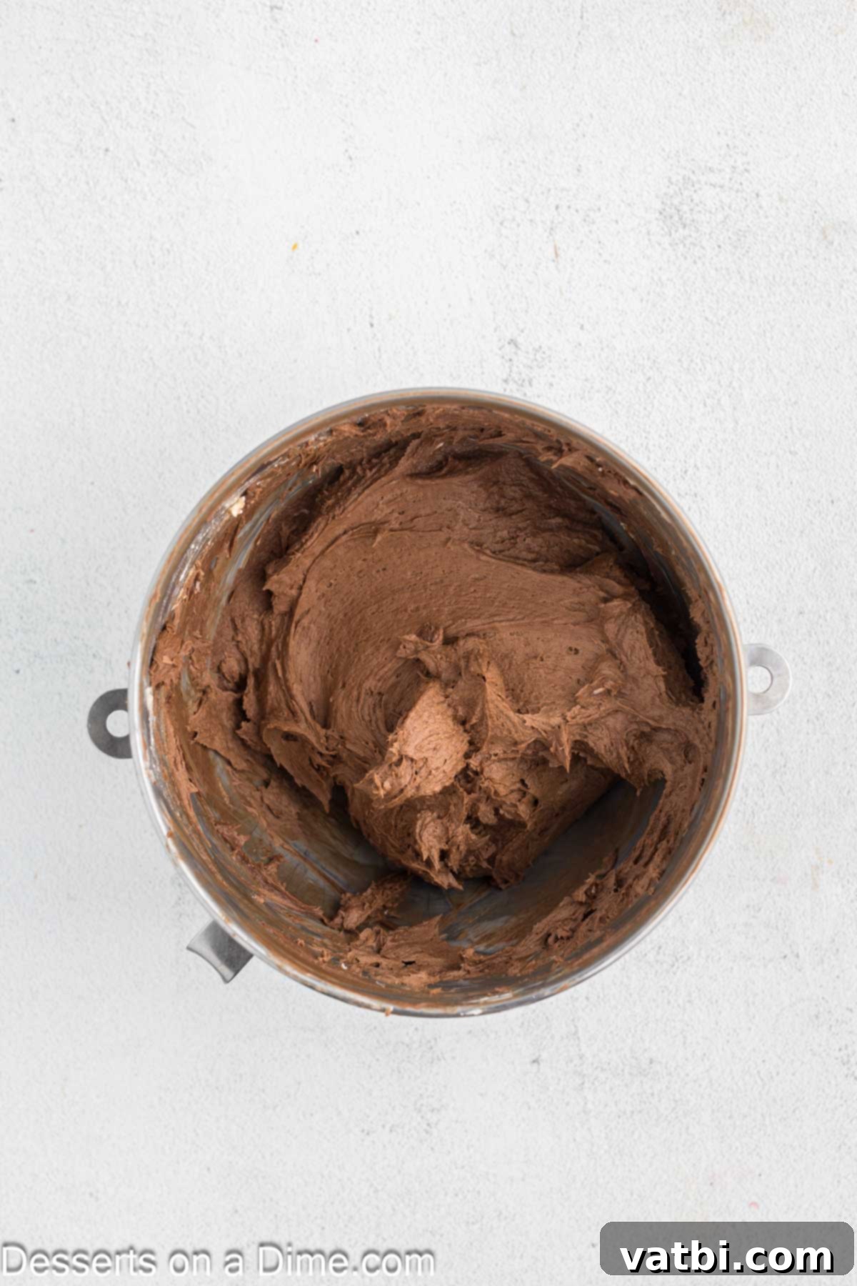 Powdered sugar and cocoa powder being added to the beaten butter in a mixing bowl, prior to combining.
