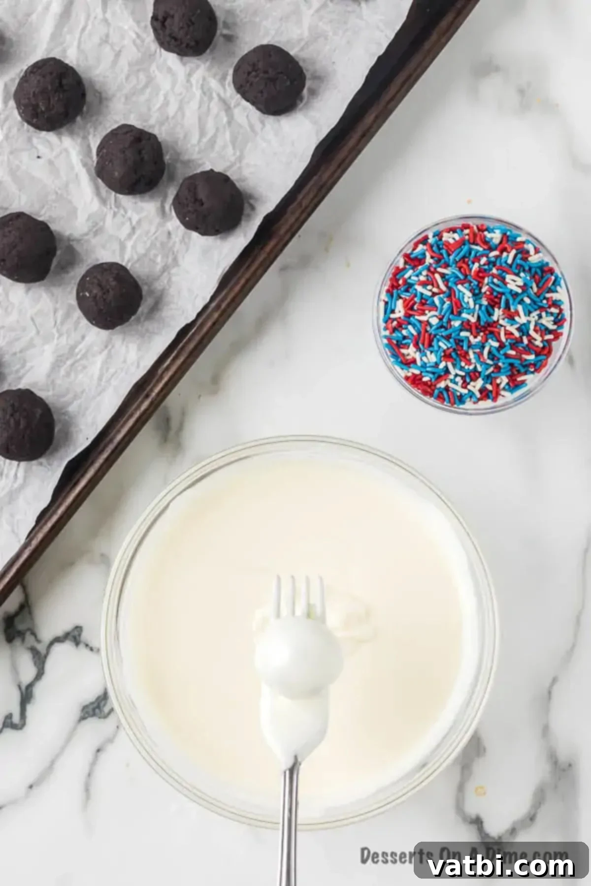 Star-Spangled Oreo Truffles 8 An Oreo Ball delicately held by a fork, being fully dipped into the smooth melted white chocolate coating.