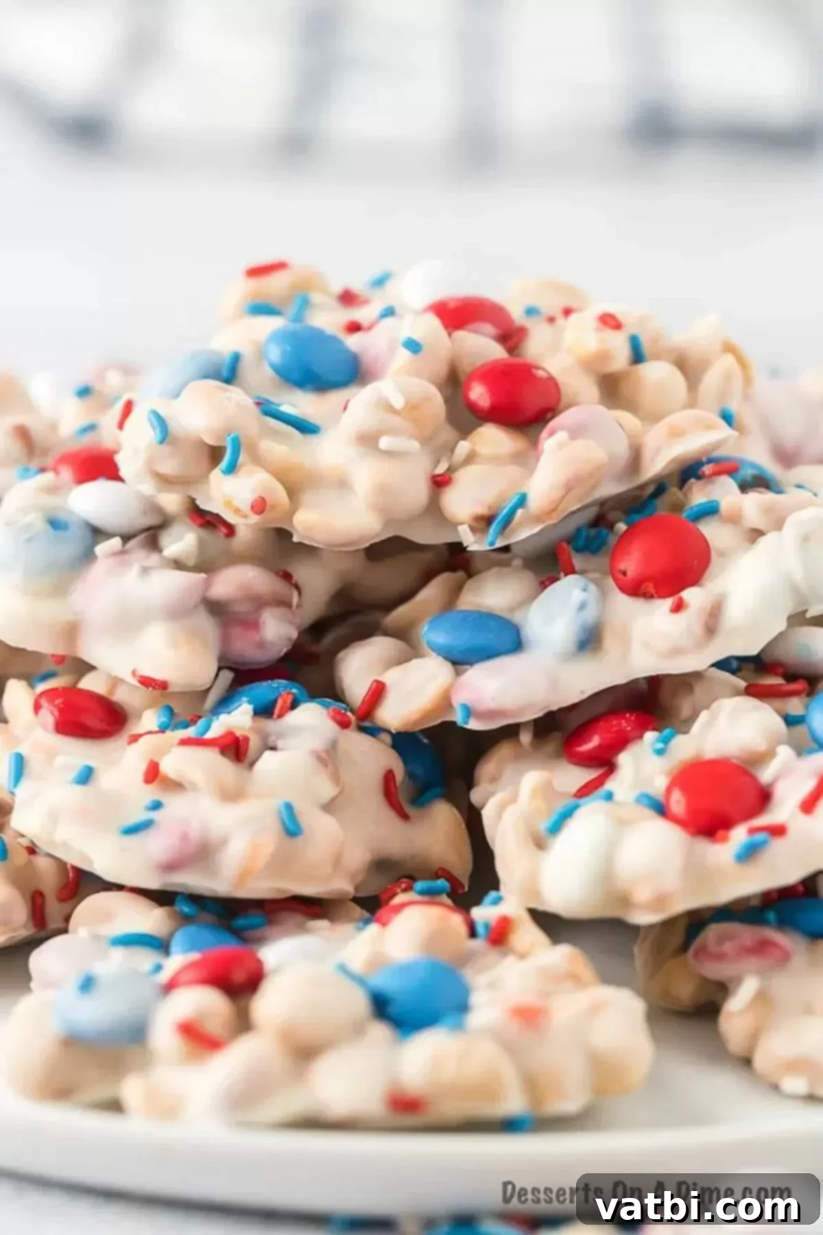 One-Pot Patriotic Peanut Clusters 8 Crock Pot cluster decorated with m&ms and sprinkles stacked on top of a serving platter.