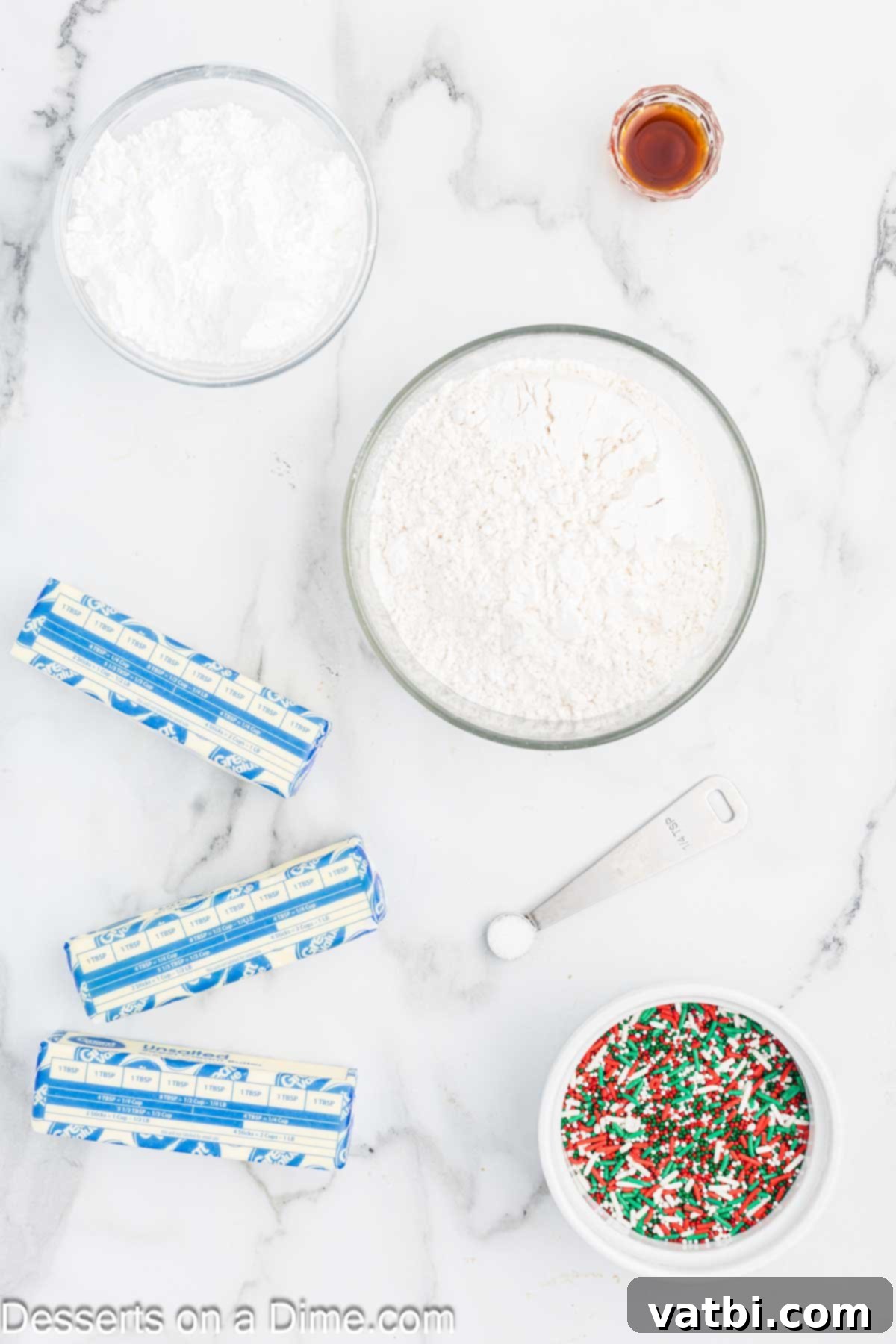 Yuletide Shortbread Delights 3 Ingredients for Christmas Shortbread Cookies laid out on a table: flour, powdered sugar, unsalted butter, vanilla extract, and colorful Christmas sprinkles.