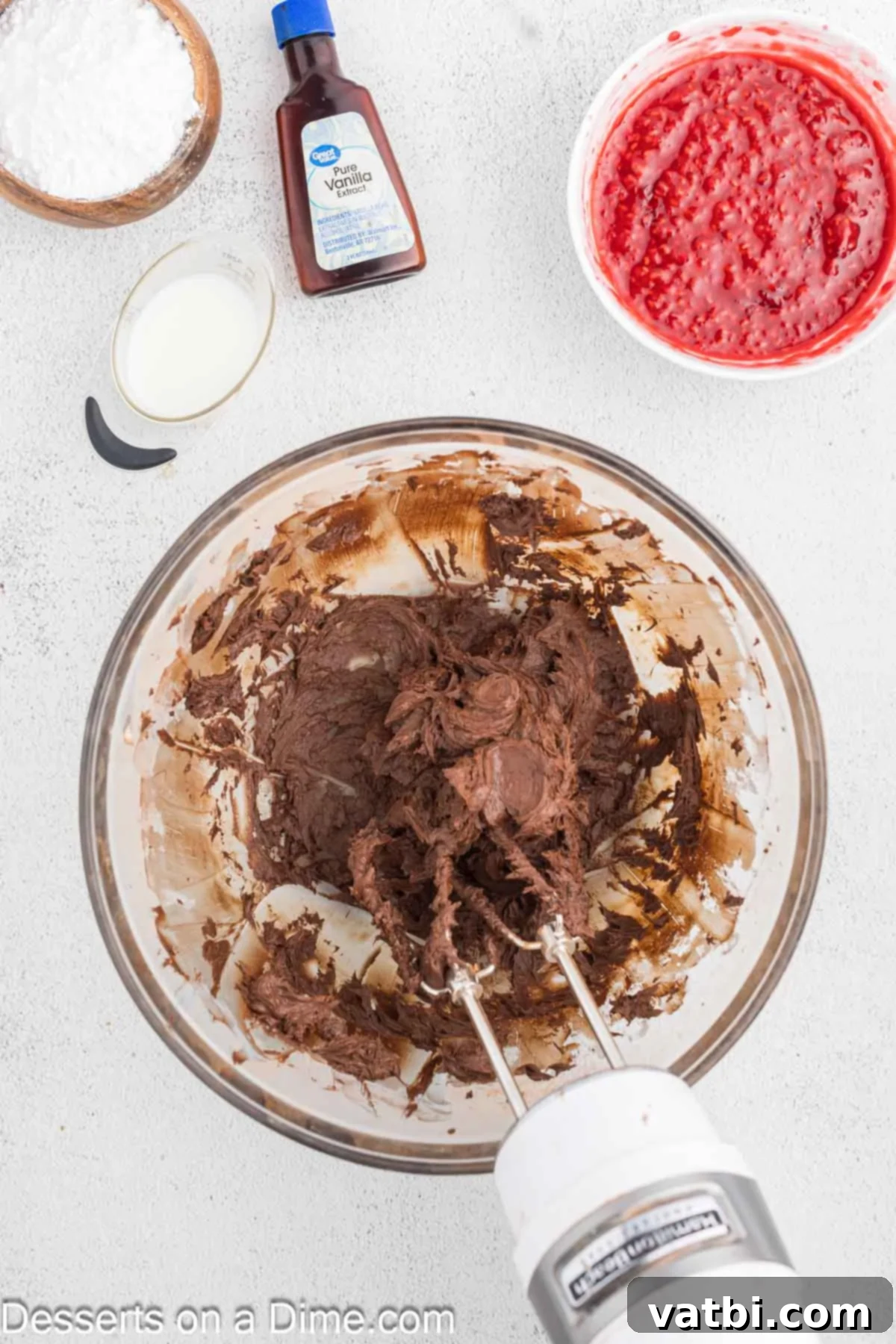 Decadent Chocolate Raspberry Cake 11 Softened butter and cocoa powder being beaten together in a bowl with an electric mixer.