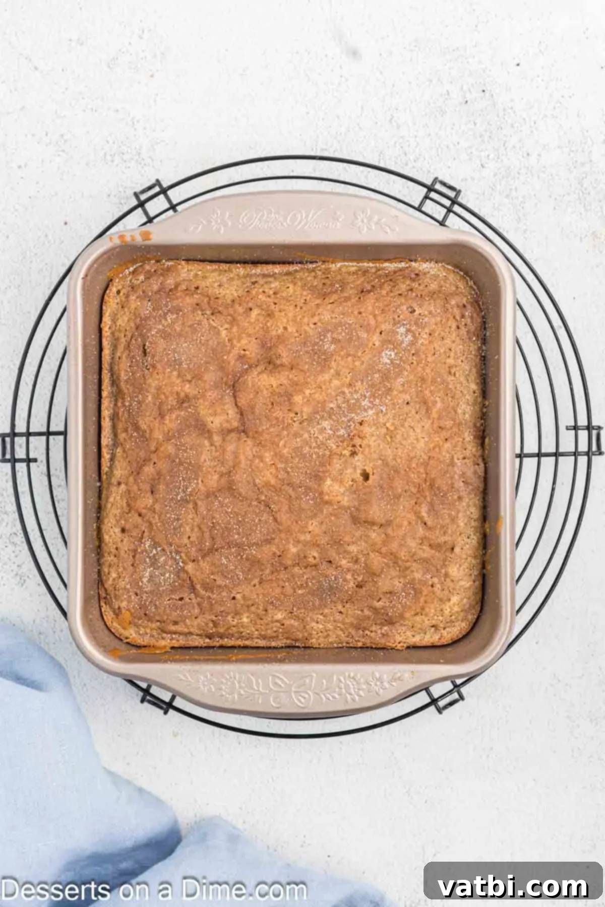 Decadent Churro Cake 13 A freshly baked churro cake, golden-brown with a crispy cinnamon sugar topping, cooling on a wire rack after being removed from the oven.