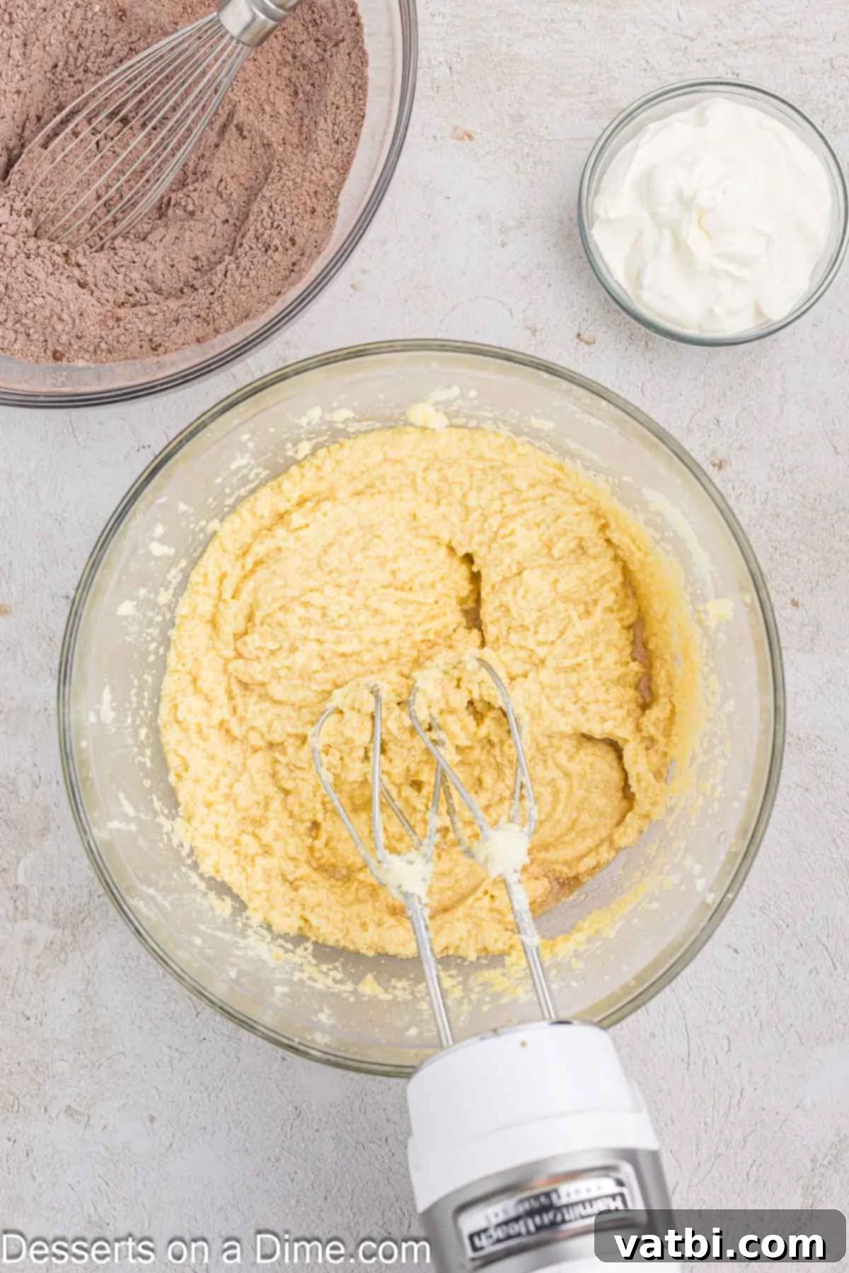 Decadent Chocolate Pound Cake 5 Fresh eggs are being gradually added, one at a time, to the creamy butter and sugar mixture in a mixing bowl, ensuring proper incorporation.