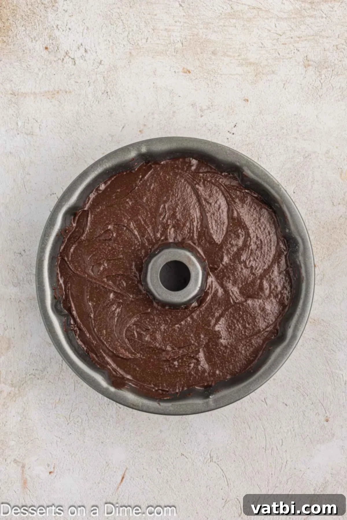 Decadent Chocolate Pound Cake 7 Thick, dark chocolate pound cake batter is carefully poured into a meticulously greased and floured bundt pan, ready for baking.