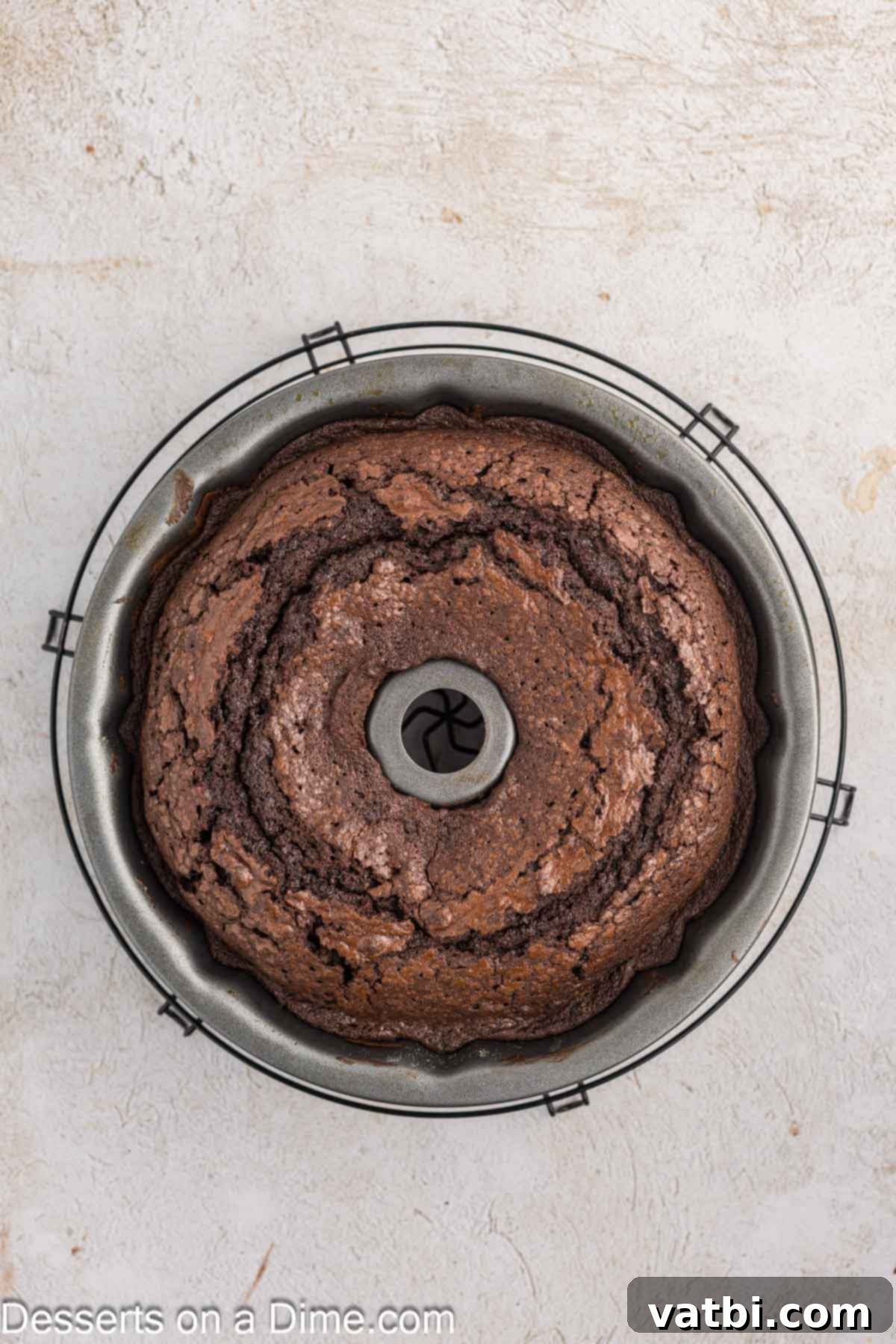 Decadent Chocolate Pound Cake 8 A freshly baked chocolate pound cake rests inside the bundt pan on a wire cooling rack, allowing it to cool slightly before inversion.
